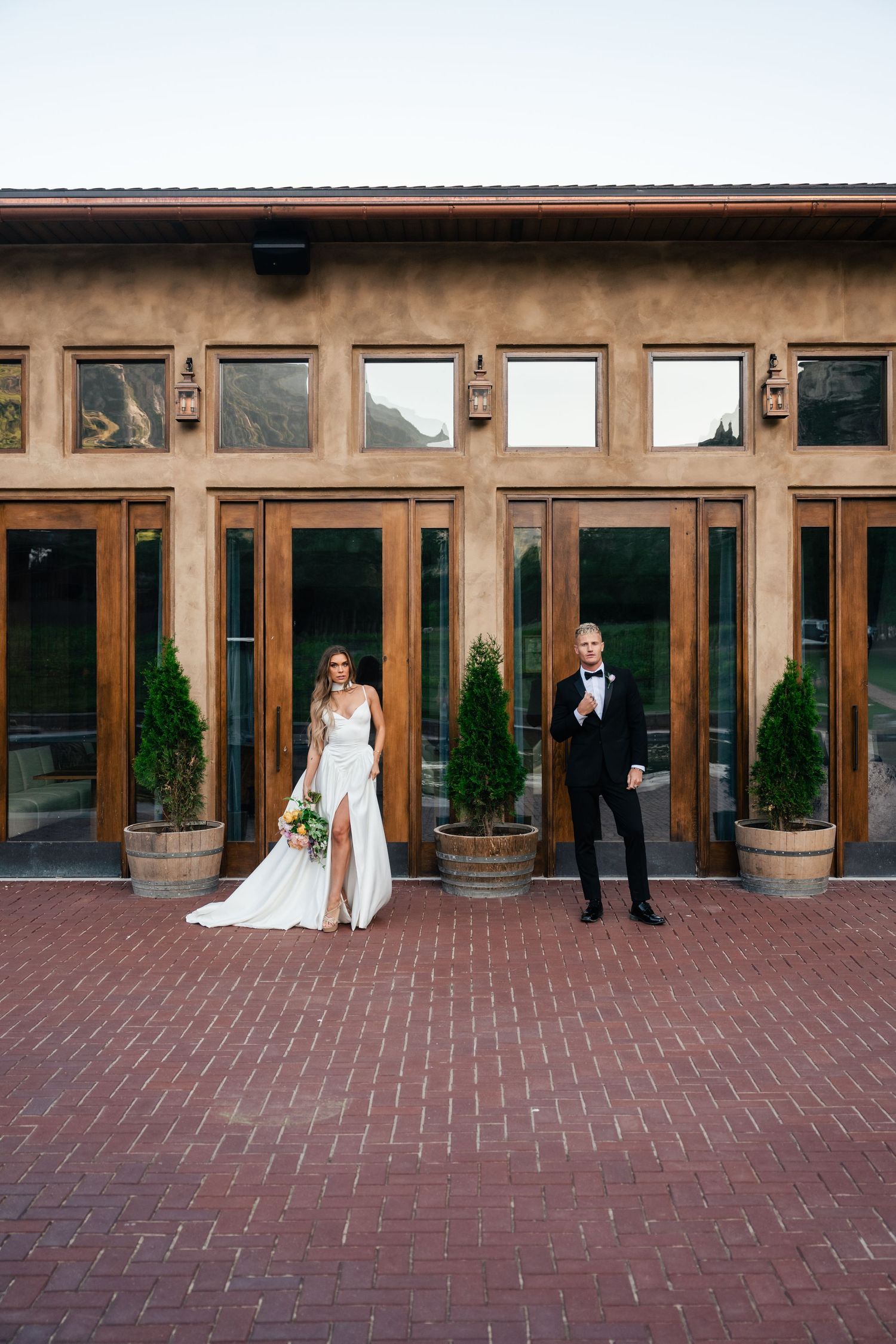 Creative sequence photo of a couple against wooden windows and brick patio at an upscale venue.