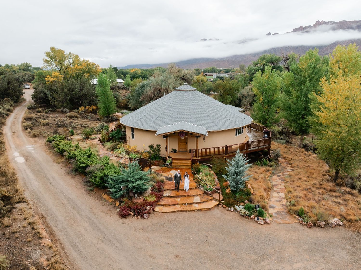 Desert yurt property with wooden deck and landscaping surrounded by autumn foliage and mountain views.