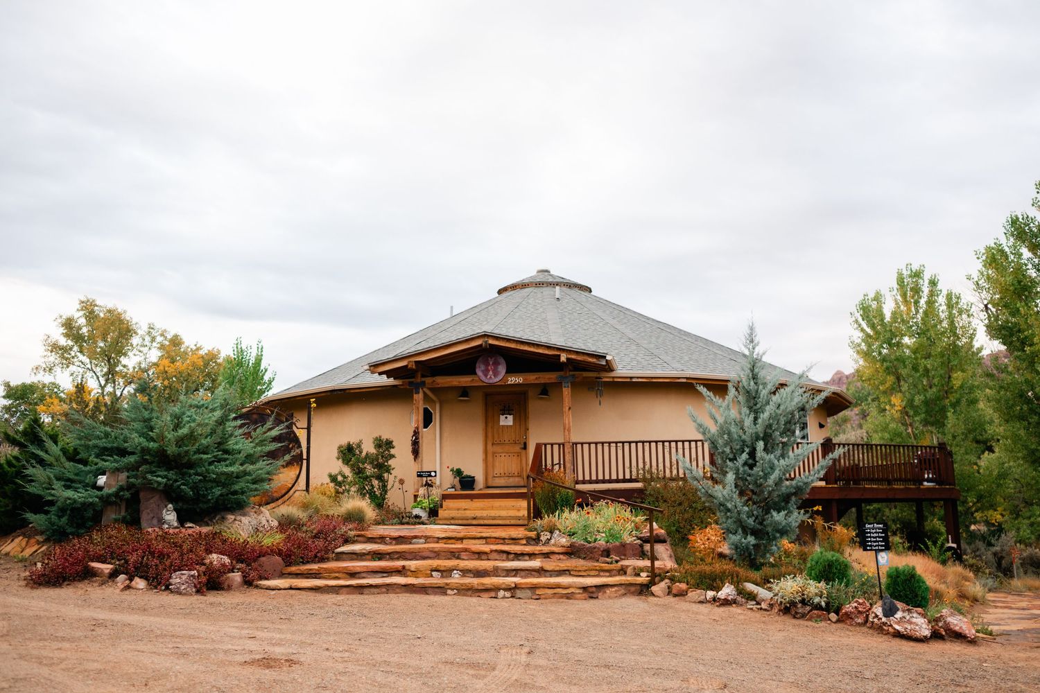Panoramic view of a rustic desert lodge with wooden decks and native landscaping against a cloudy sky.