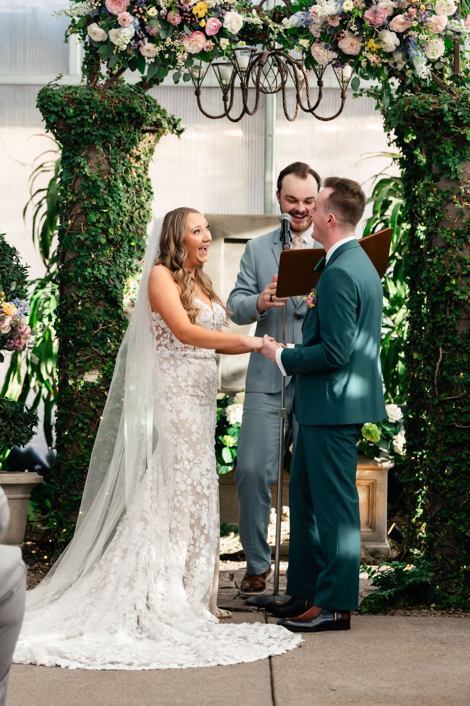 Wedding ceremony under floral arch with elegant white lace dress and greenery decor at Cactus and Tropicals in Draper. Coley Cook.