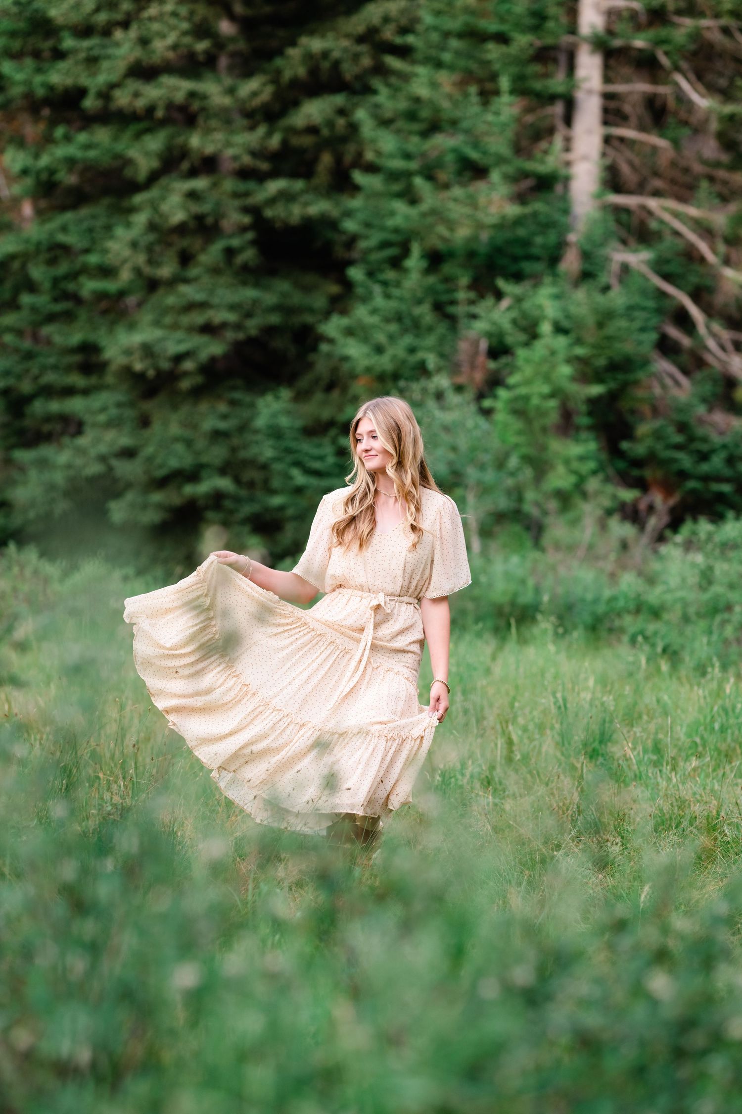 A flowing cream-colored dress twirls gracefully in a lush green meadow on a summer day.