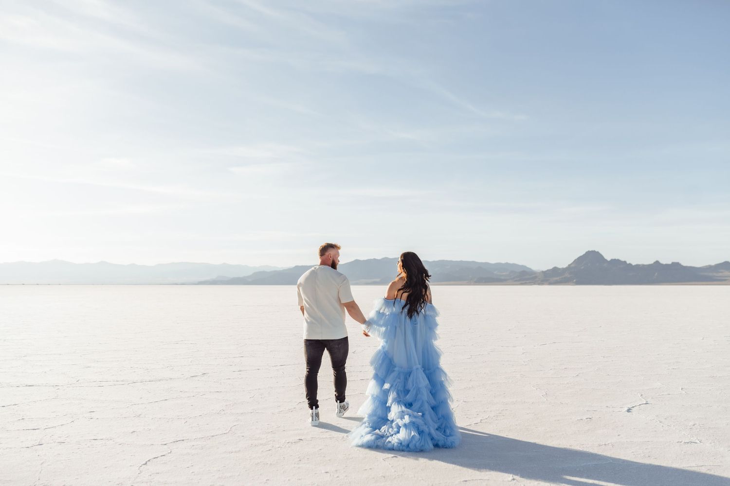 Utah Salt Flats Photographer. Two people in formal attire walk across the stark white landscape of the Bonneville Salt Flats in Utah.