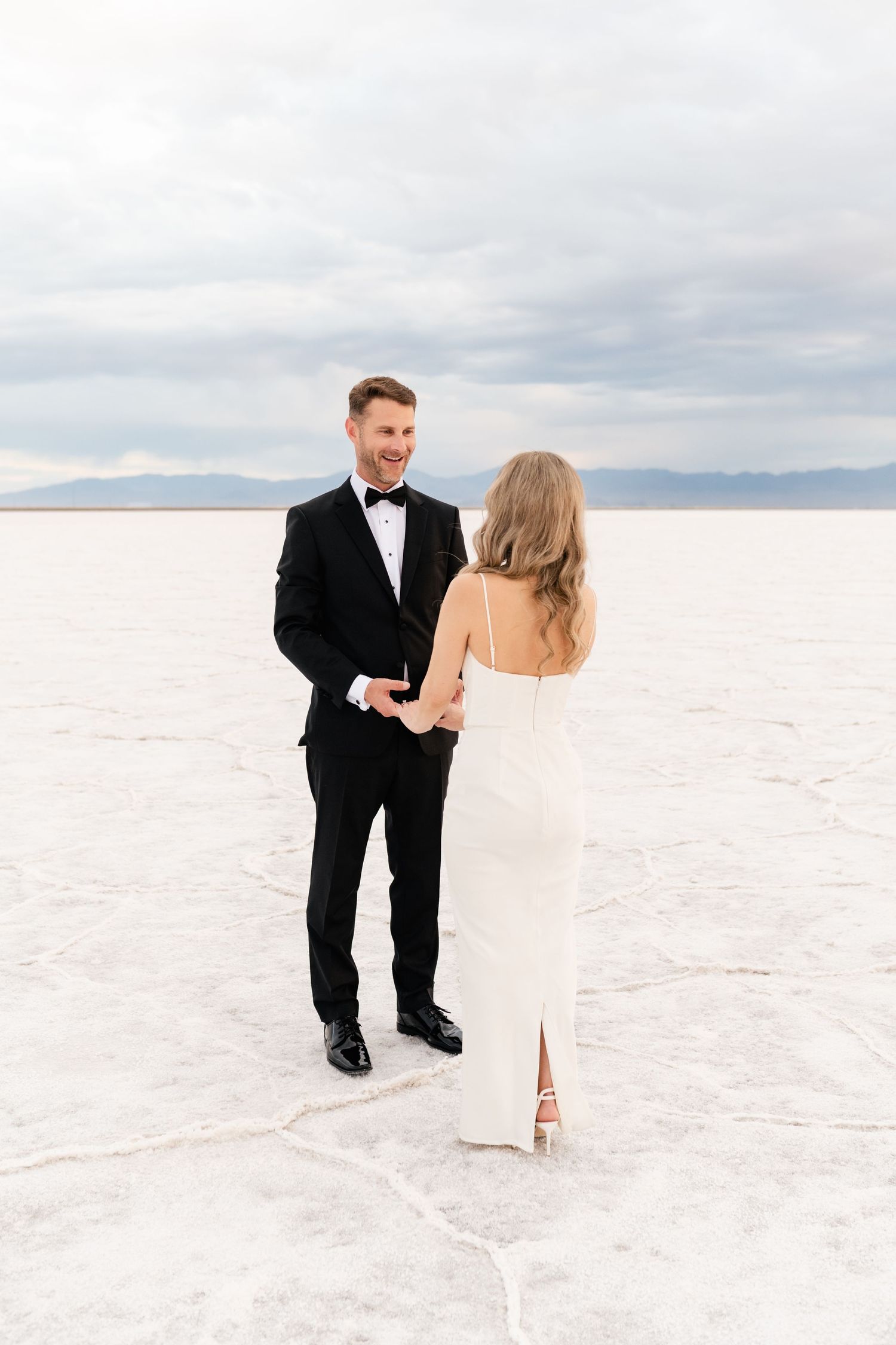 Salt Flats Elopement Photographer. A couple in wedding attire dances playfully on the expansive salt flats landscape.