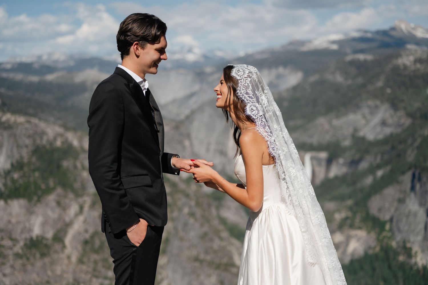 Bride and groom exchange vows outdoors at Yosemite with stunning mountain views behind them.