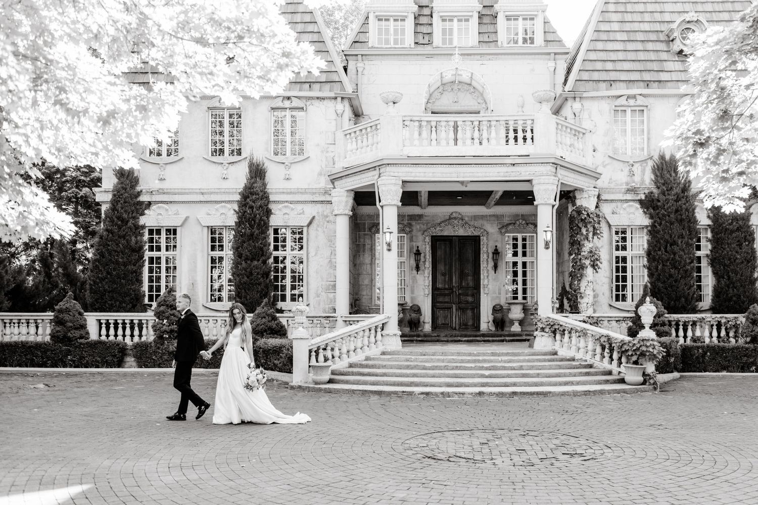 Classic white mansion with elegant columns and grand entrance stairs in black and white photography.