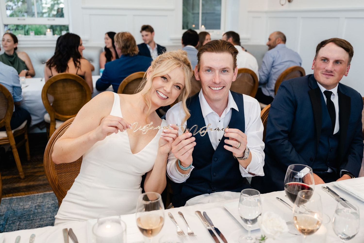 Wedding reception guests enjoying dinner at elegant white-tablecloth restaurant.