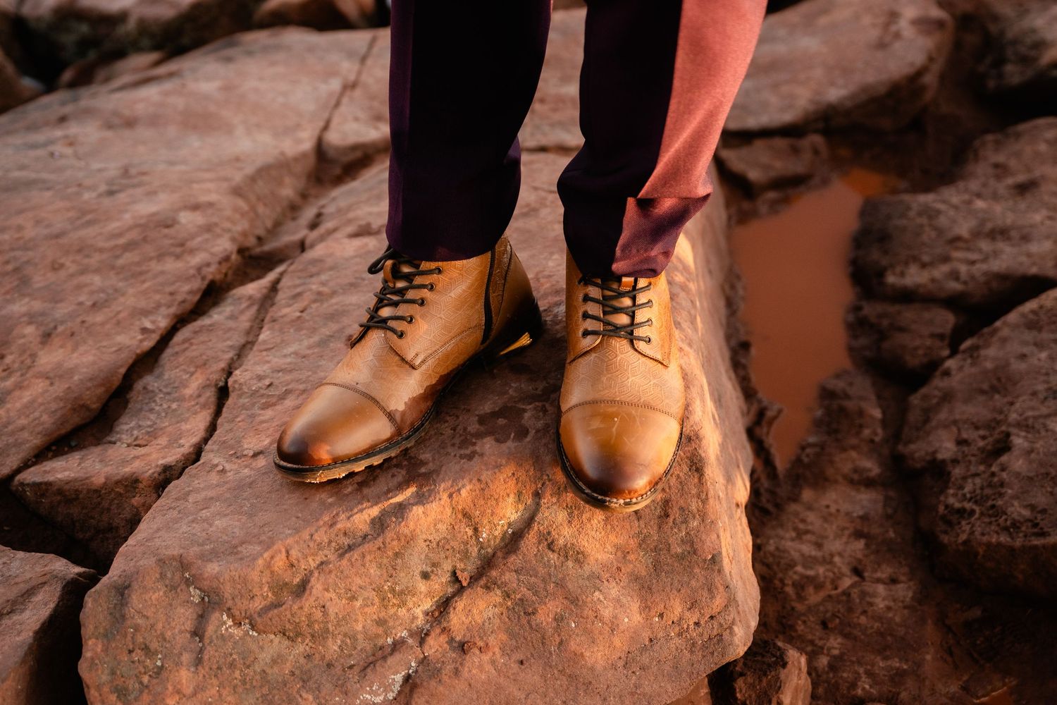 Close-up of brown leather boots standing on red rock formations.