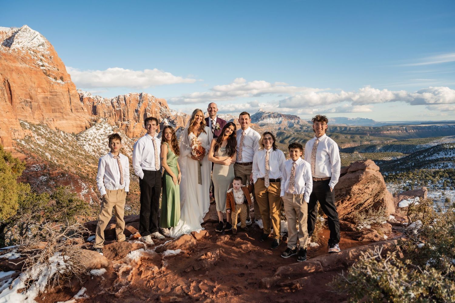 Wedding group photo on red rocks with panoramic mountain views in Utah.