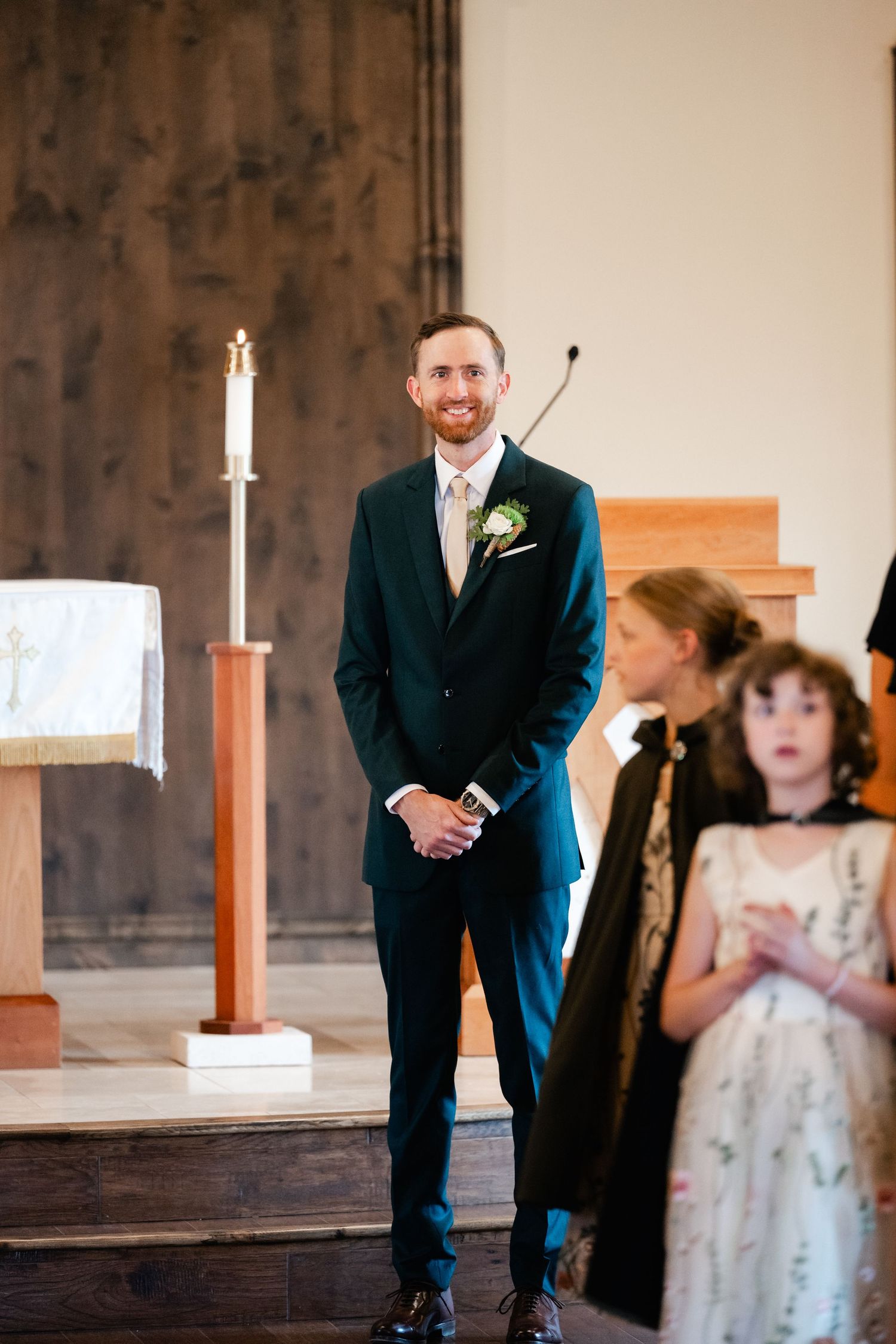 A wedding ceremony unfolds in an elegant chapel with wooden pews and candlelit ambiance.