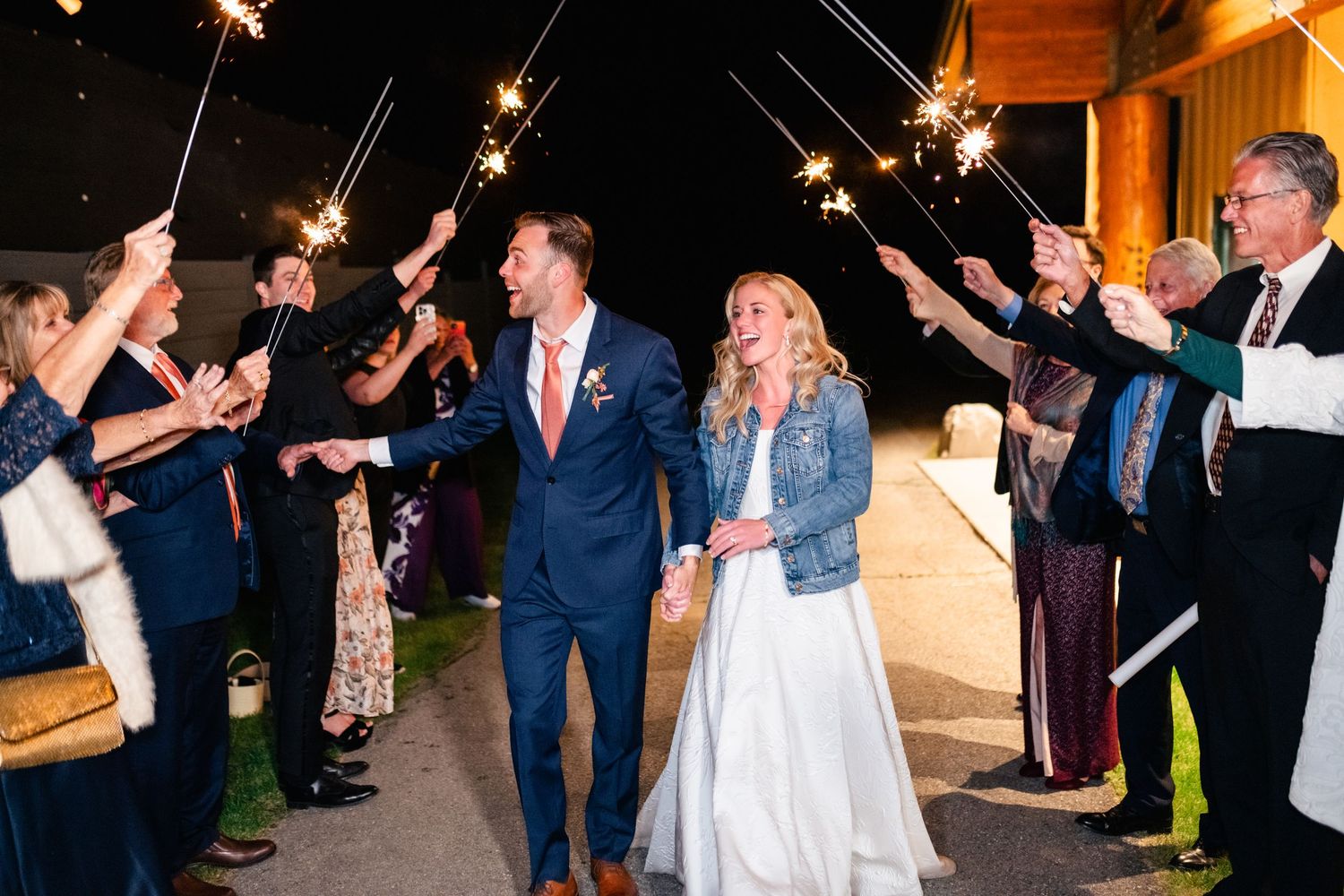 Wedding guests form an exit line with sparklers at an outdoor evening celebration.