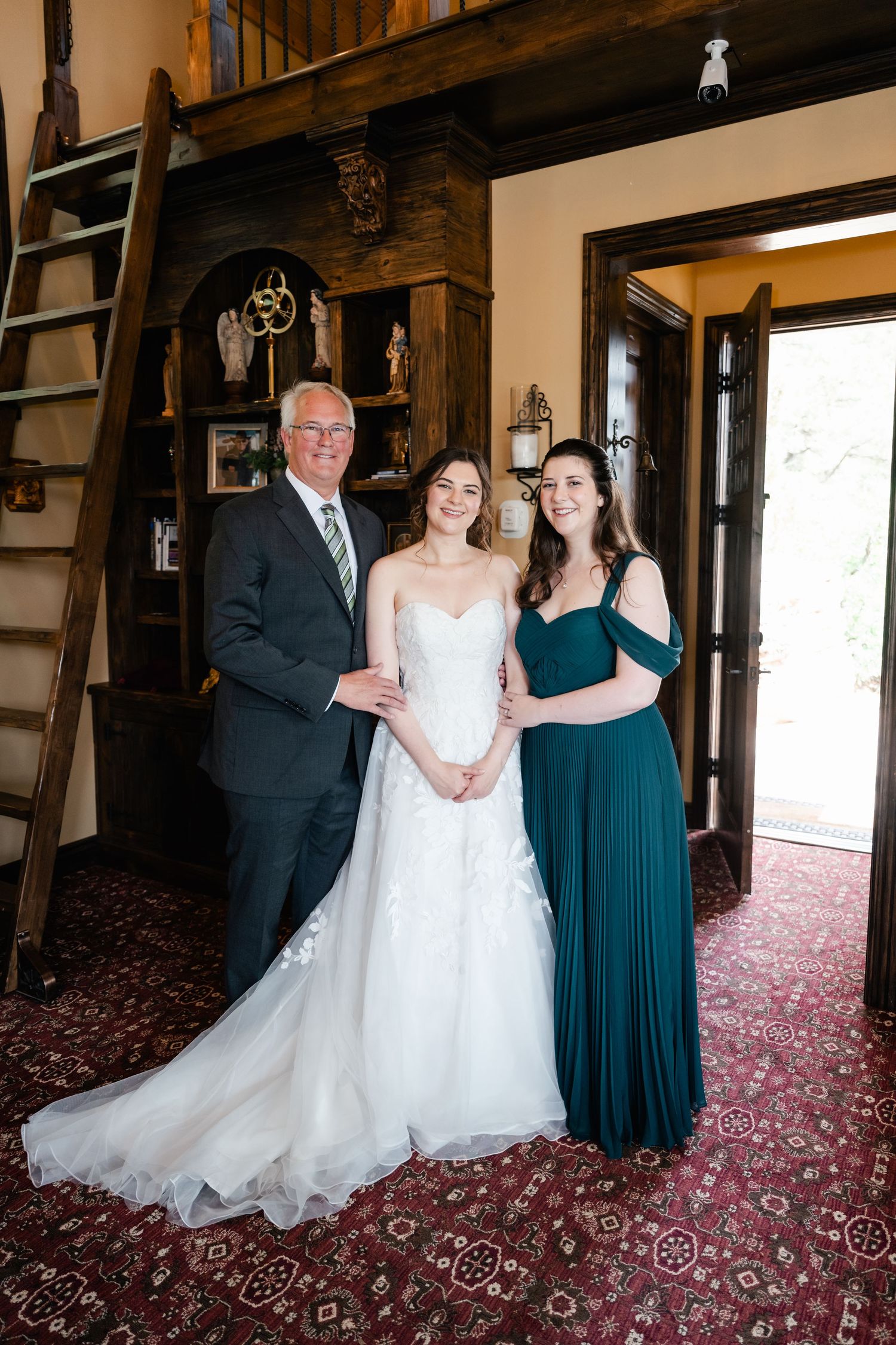 Wedding party poses in formal attire against rustic wooden interior.