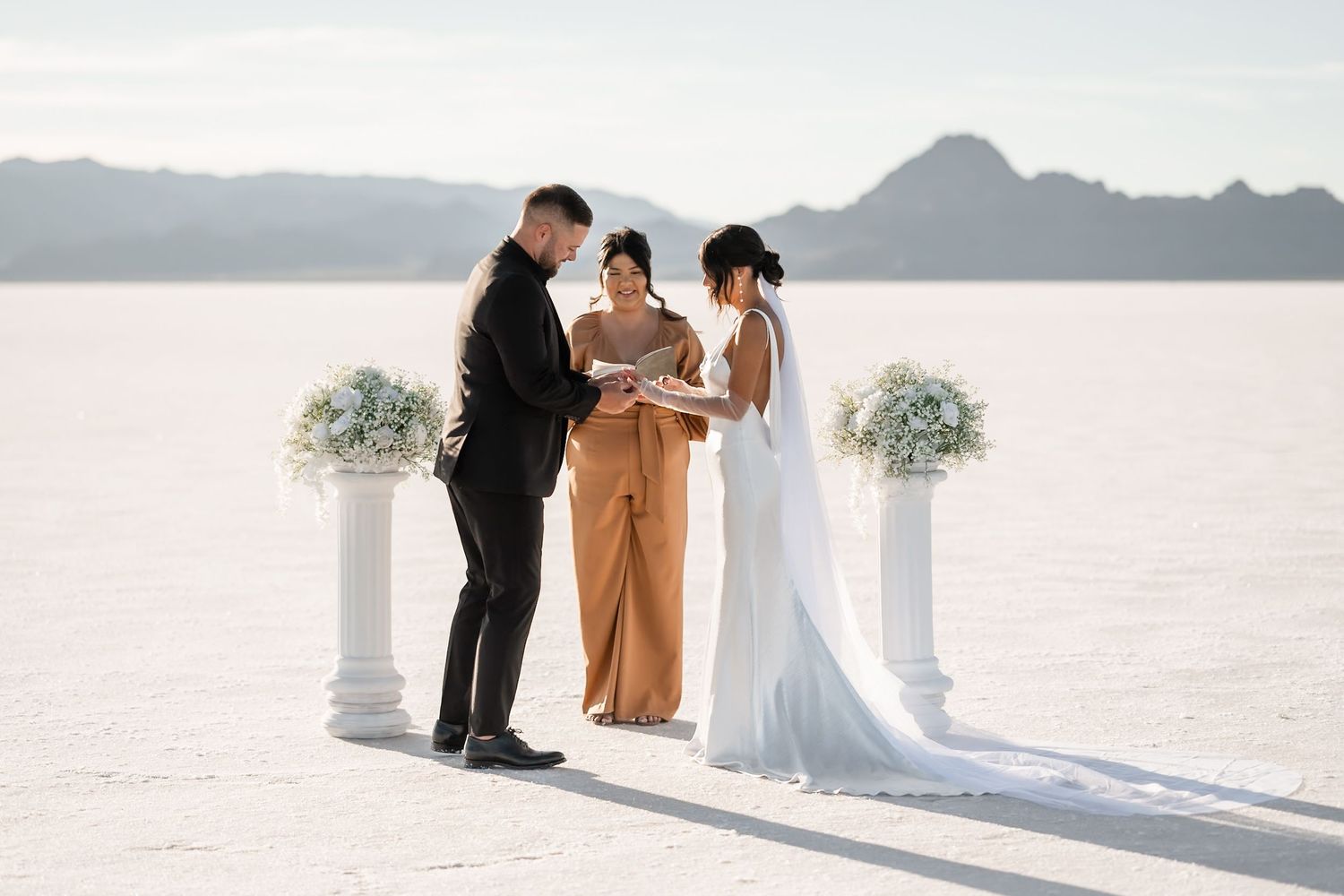 Intimate wedding ceremony taking place on vast salt flats with mountain views.