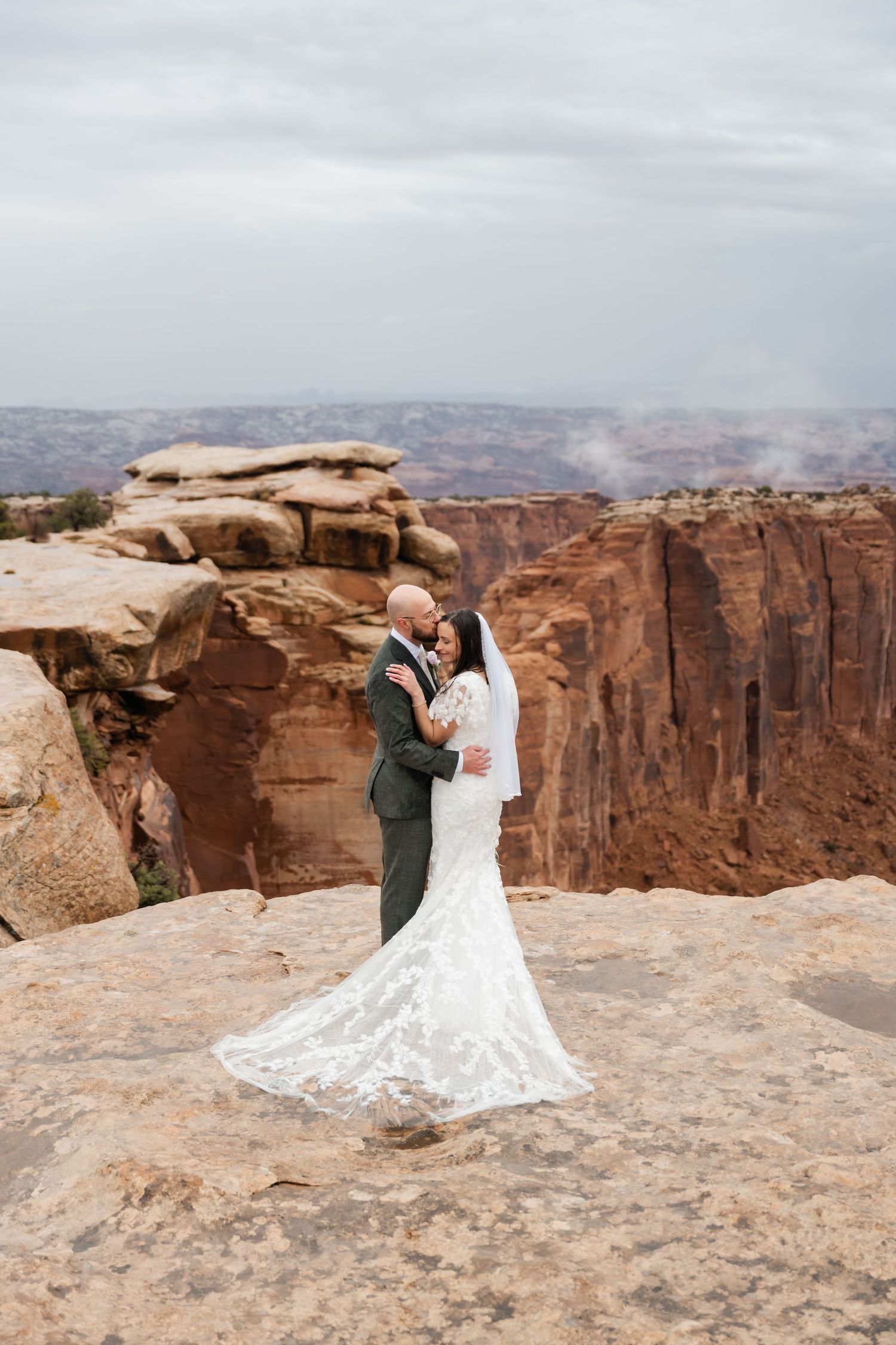 A wedding couple shares an intimate moment on the edge of a majestic canyon overlook.