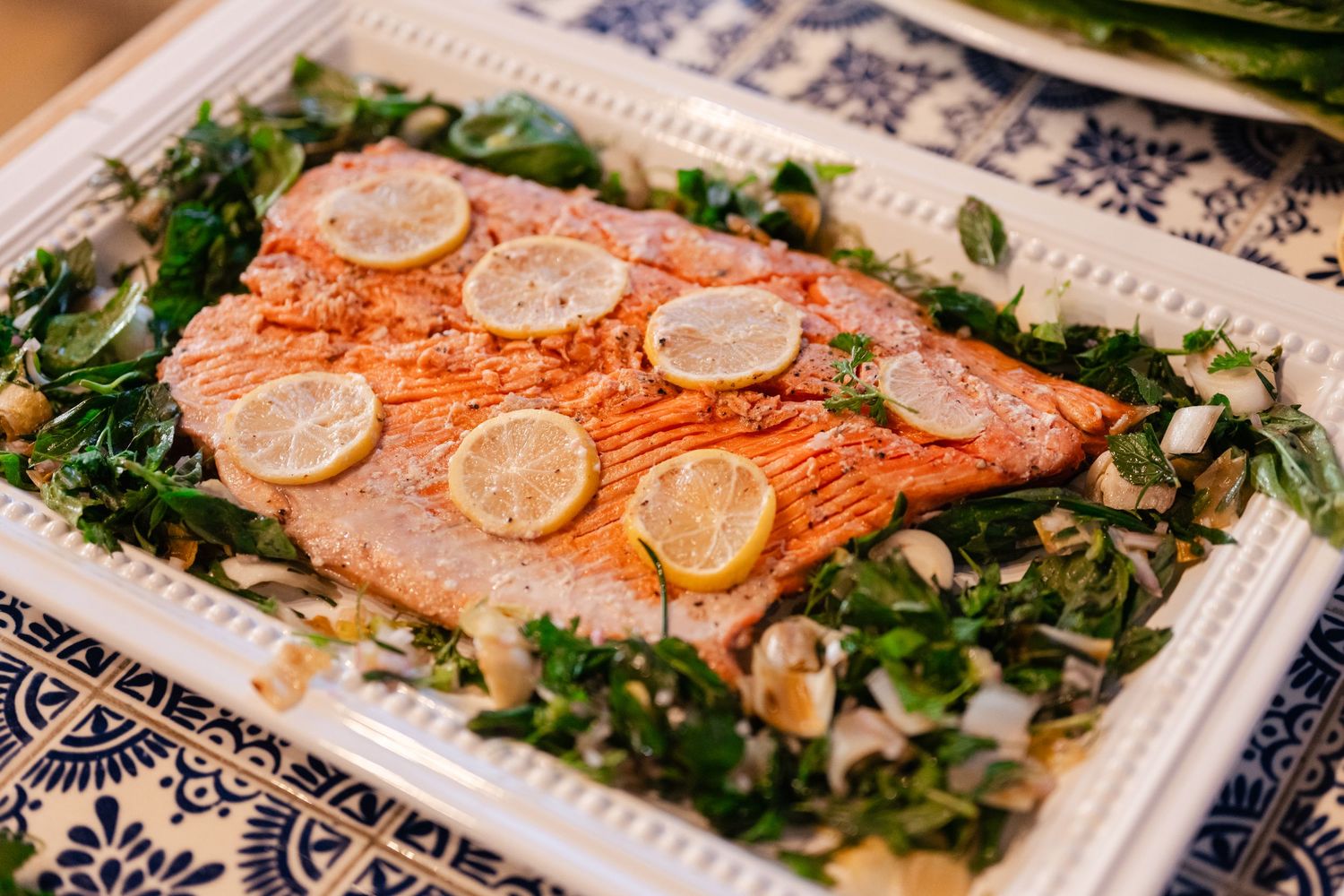 Baked salmon fillet garnished with fresh herbs and lemon slices served on a decorative platter.