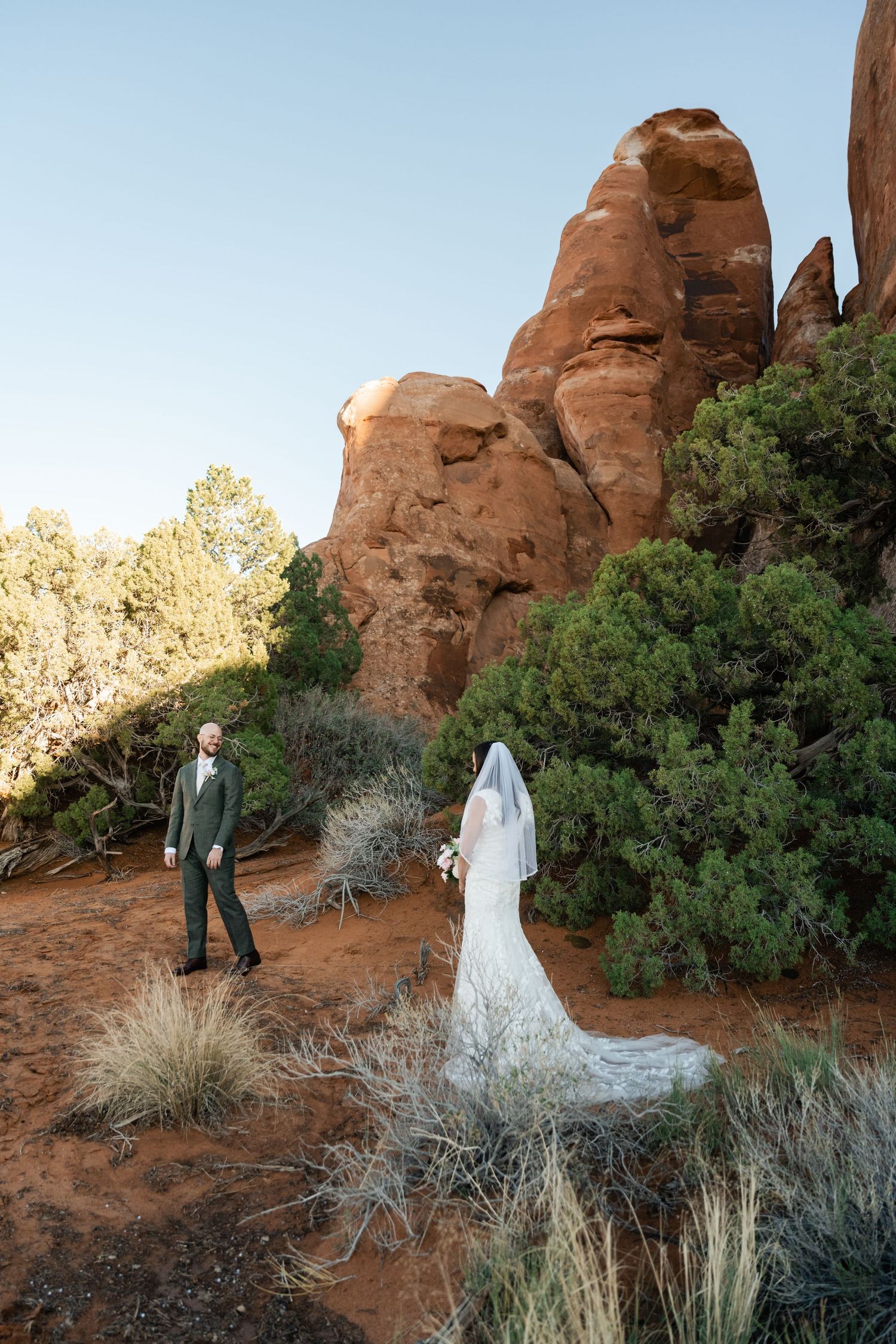 A wedding photoshoot among majestic desert arches and native vegetation.