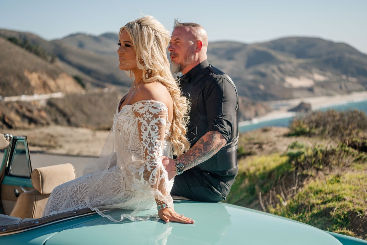 Couple enjoying a romantic moment in vintage turquoise convertible by the coast.