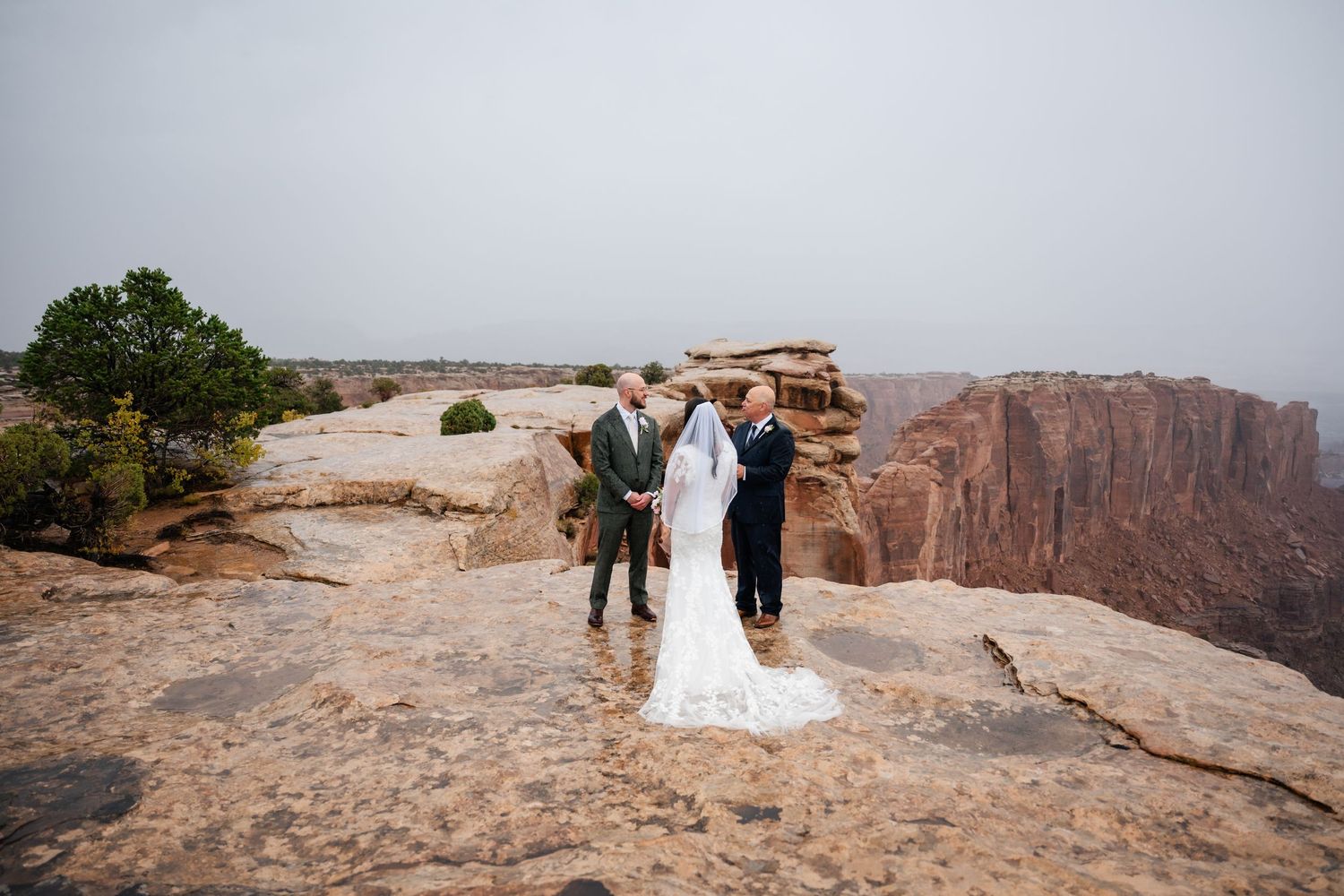 Intimate wedding ceremony taking place on scenic desert cliff edge.
