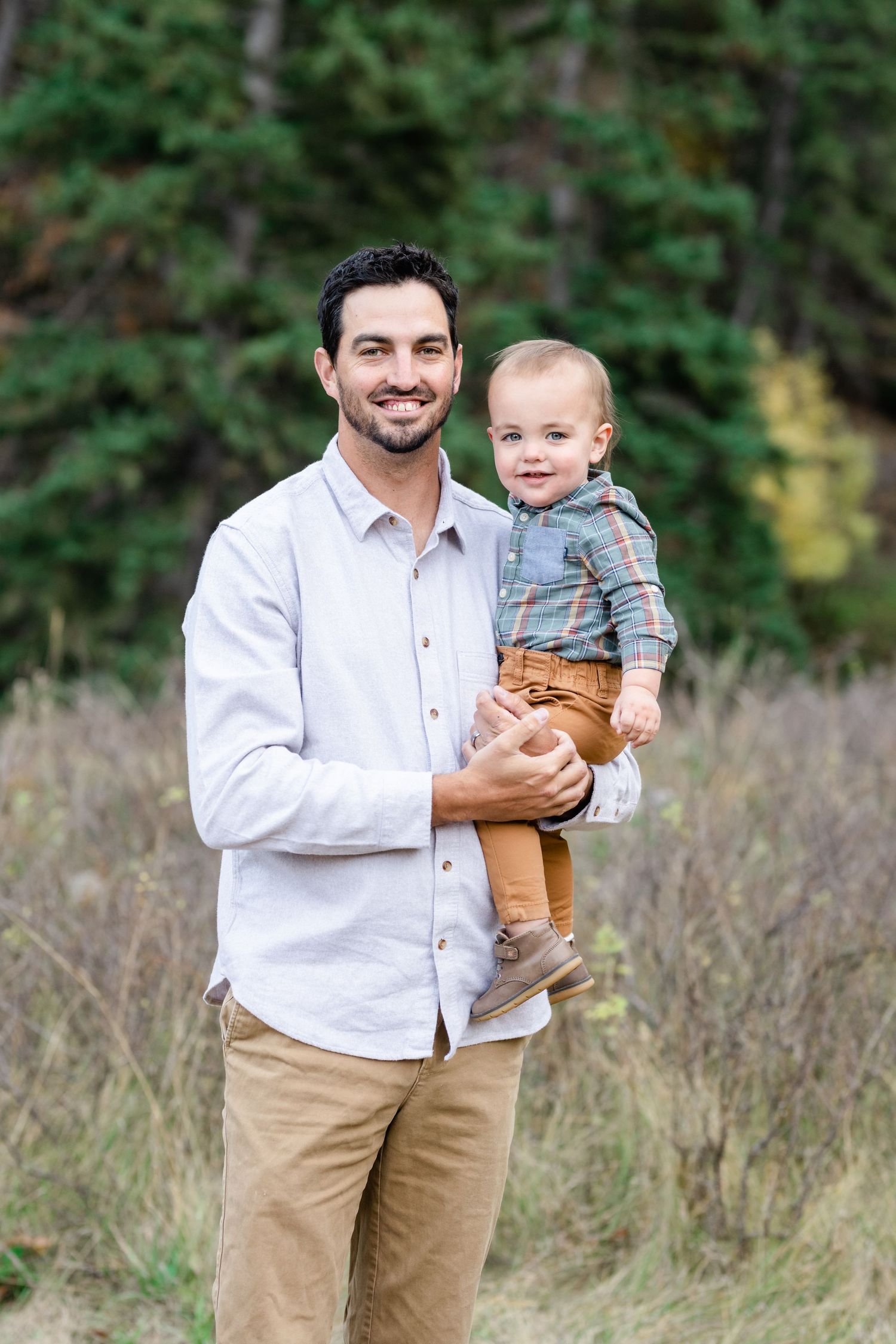 Parent and toddler smiling together in natural outdoor setting.