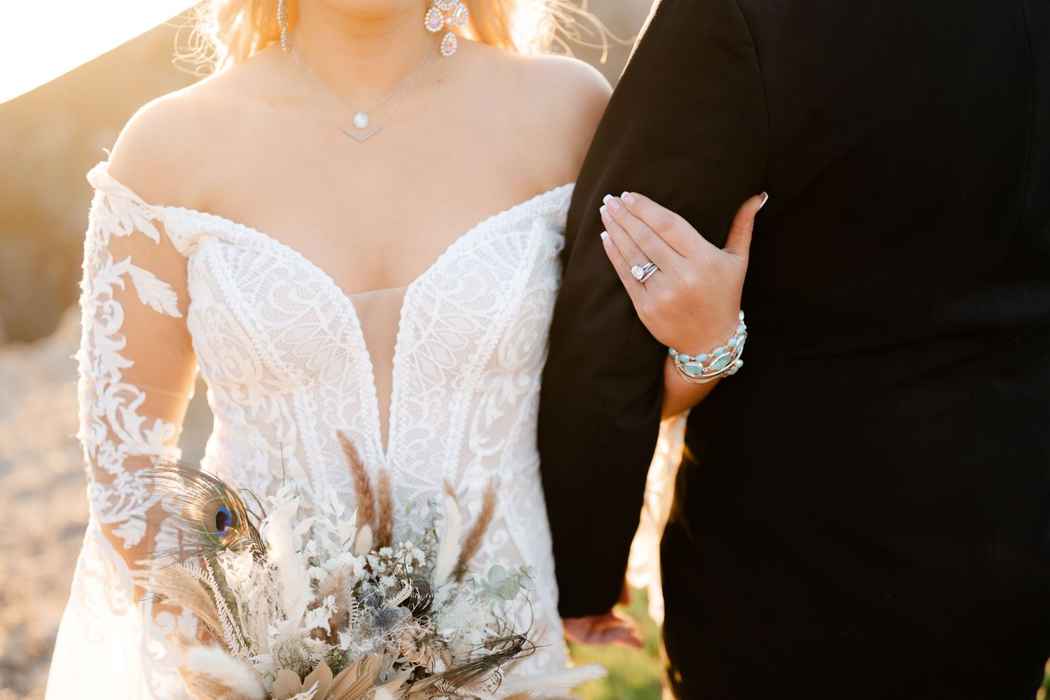 Close-up detail of a white lace wedding dress with intricate beading glowing in sunset light.