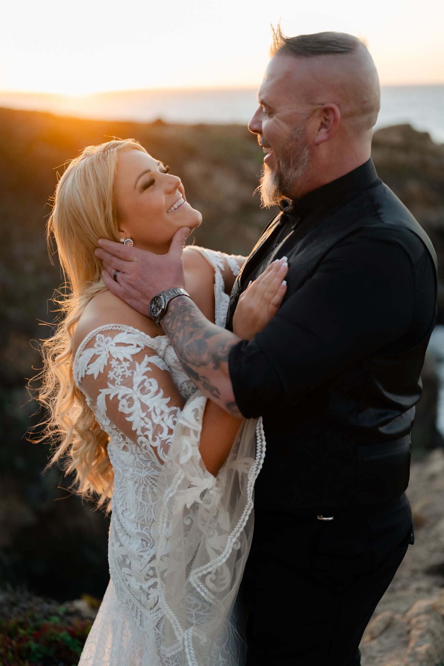 A couple shares a romantic moment on a coastal cliff during golden hour.