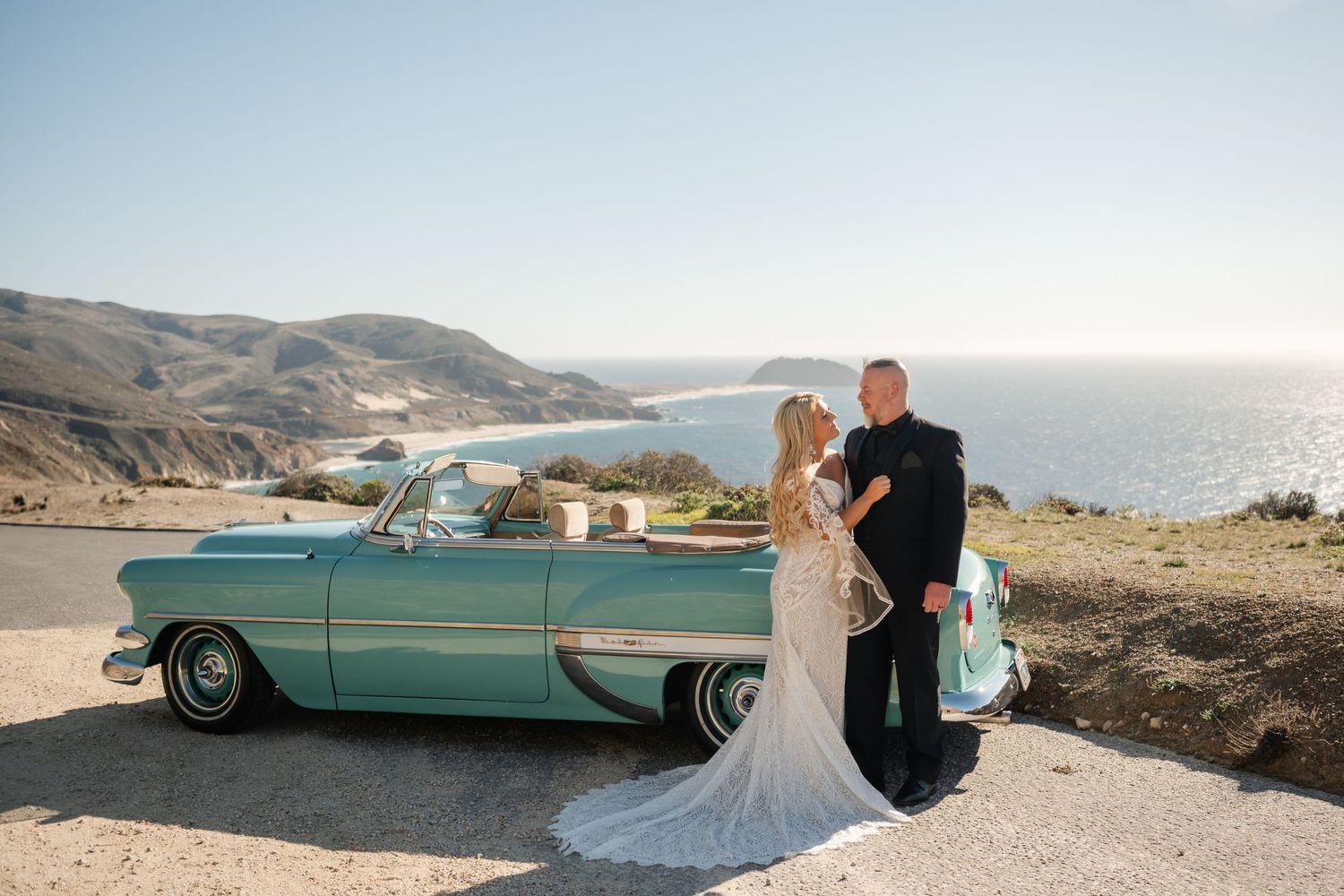 A mint green classic car parked along the California coastline.