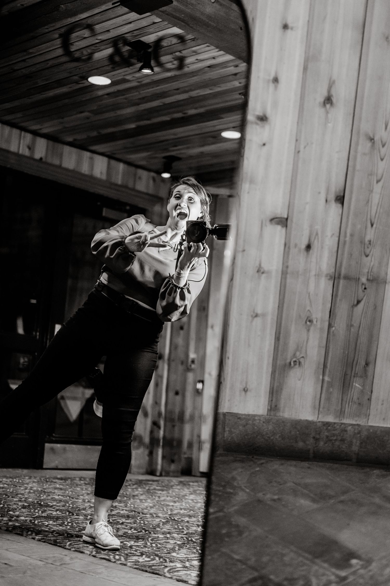 Black and white photo of a performer dancing energetically in a rustic wooden venue.