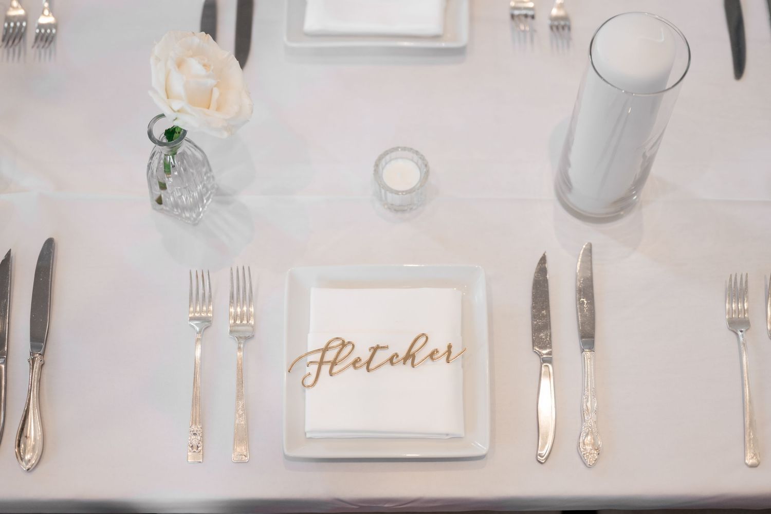 Formal wedding reception table setting with white linens and elegant place settings.