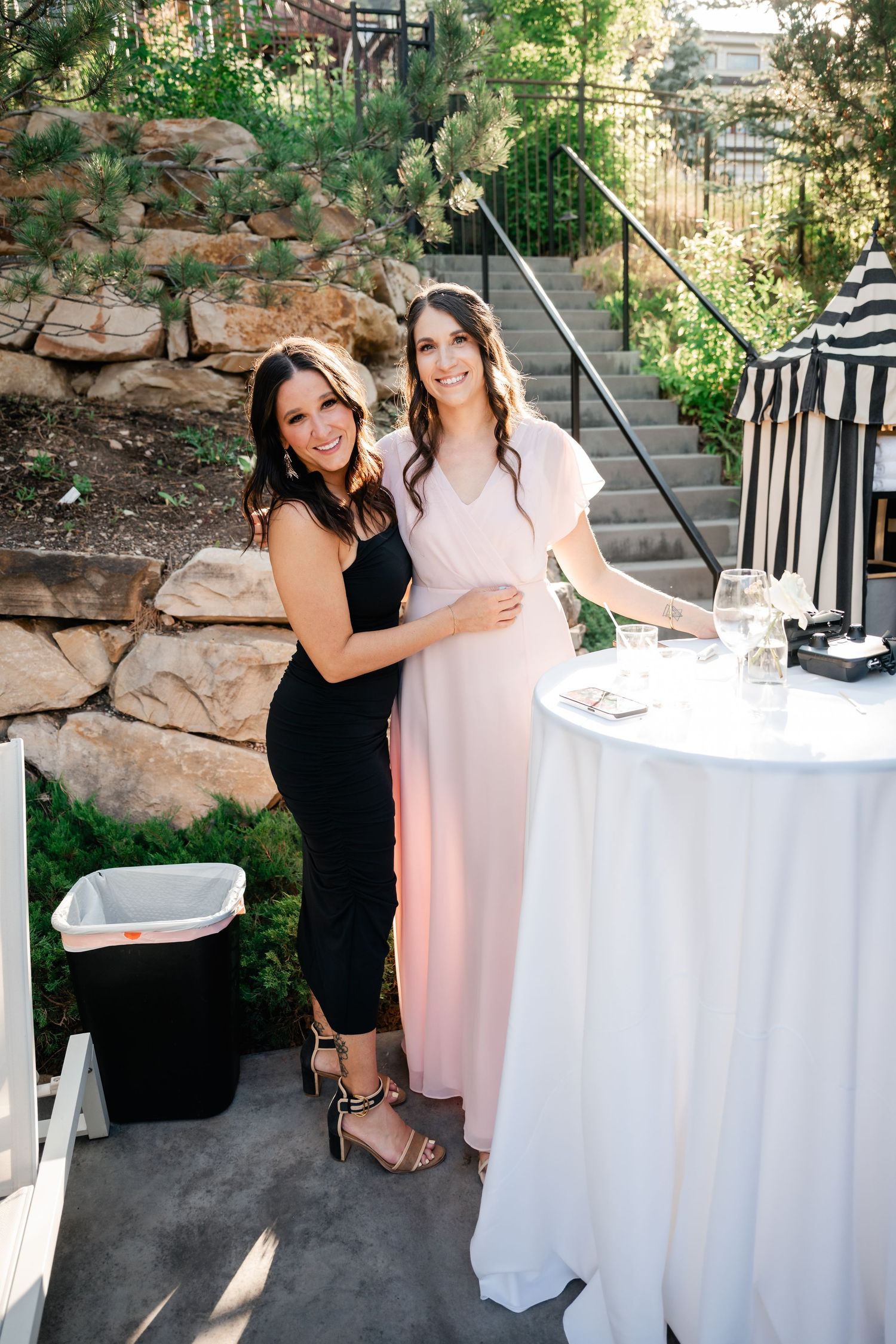 Friends celebrating at an outdoor event with white cocktail tables.