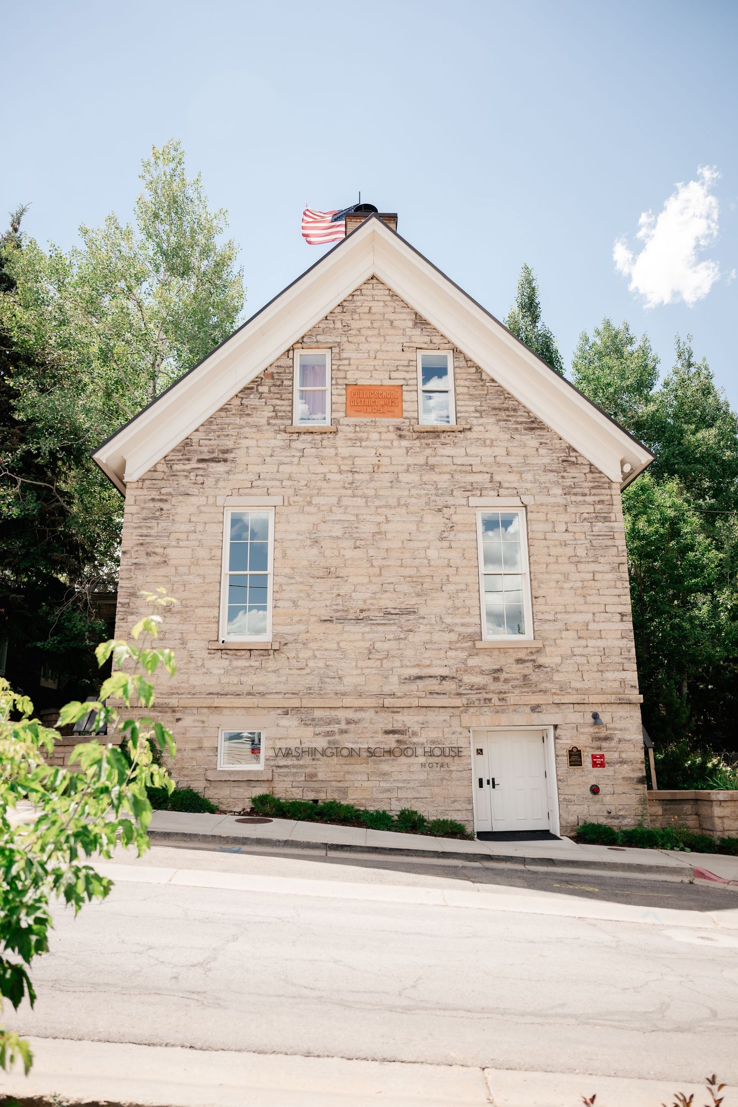 Stone building exterior with multiple windows and an American flag shown from different angles.