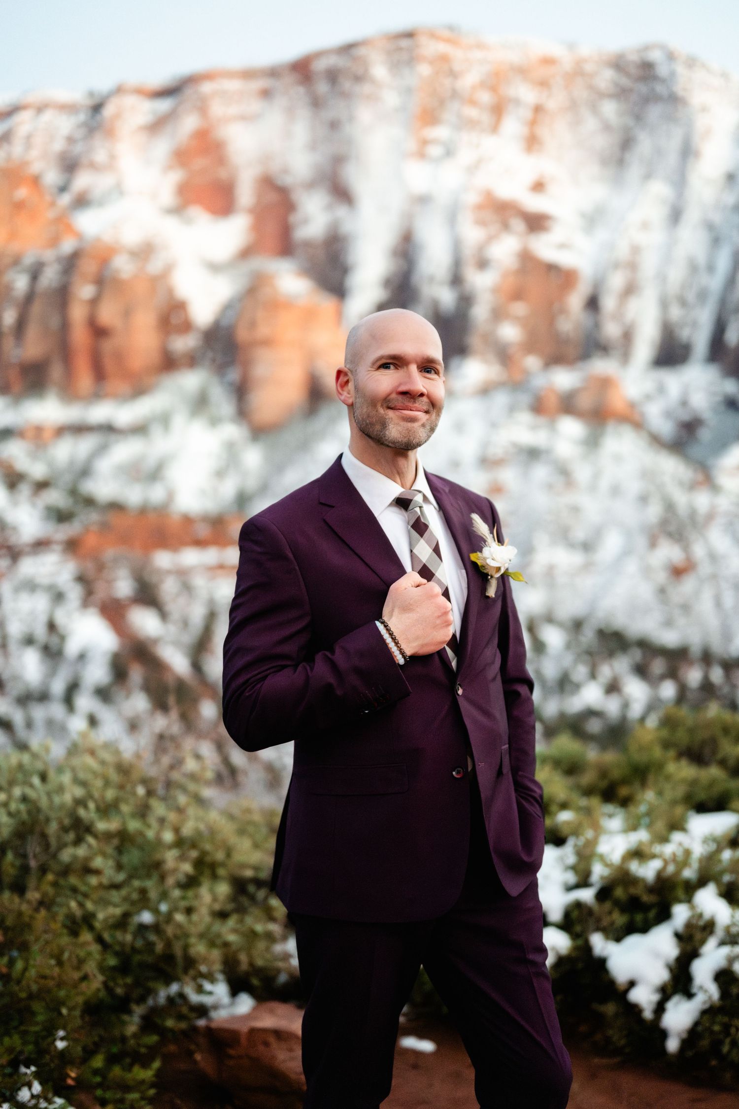 Portrait series against snowy red rock cliffs wearing a burgundy suit.
