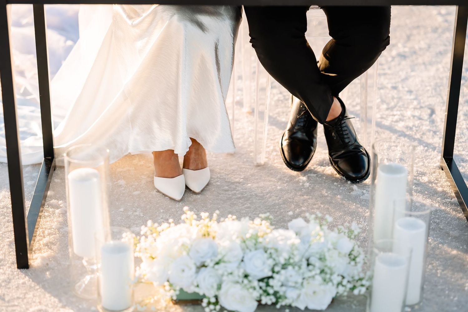 Wedding shoes and floral arrangements displayed on crystalline salt flat surface.