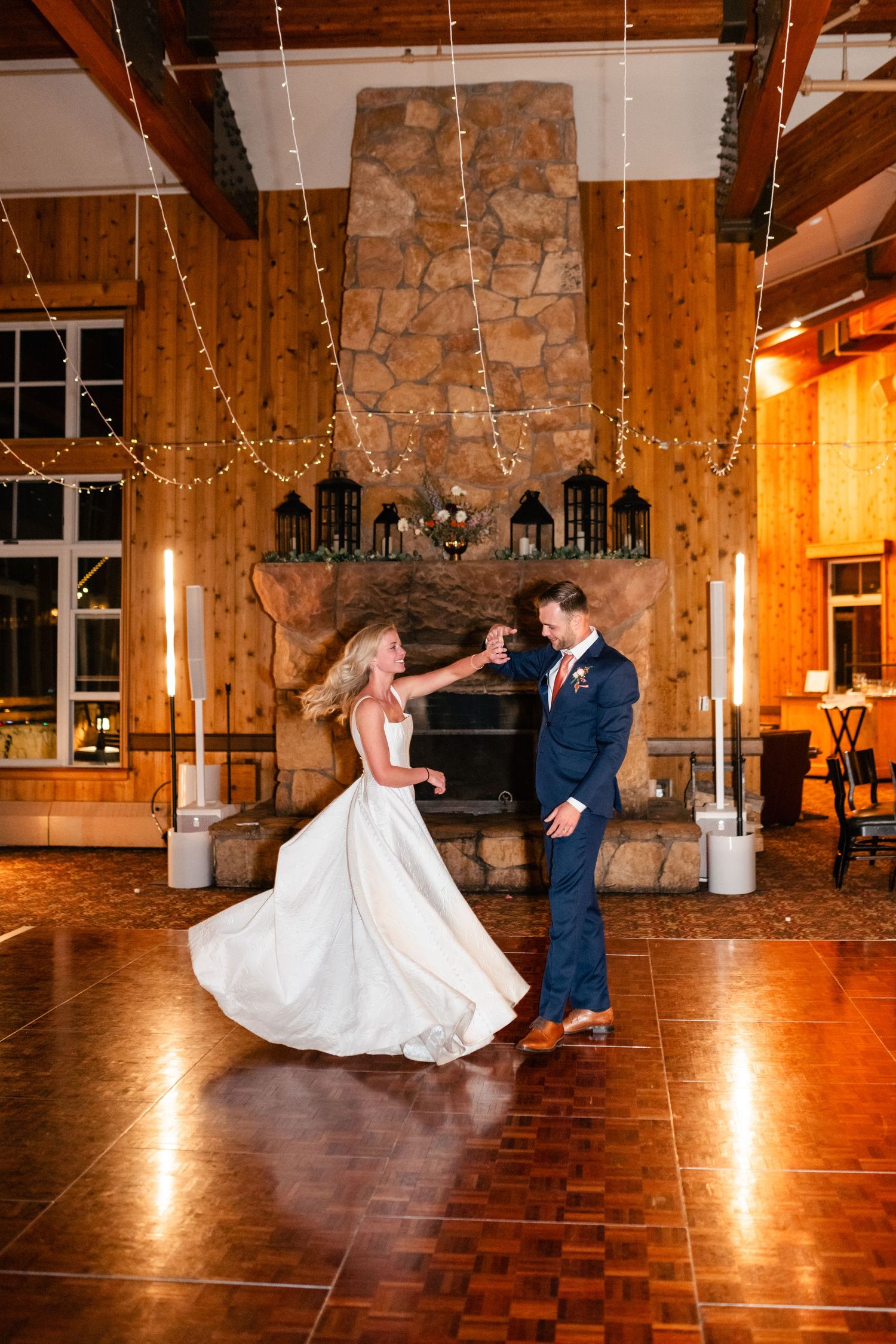 Couple executes playful dance moves during their wedding reception in a rustic venue.