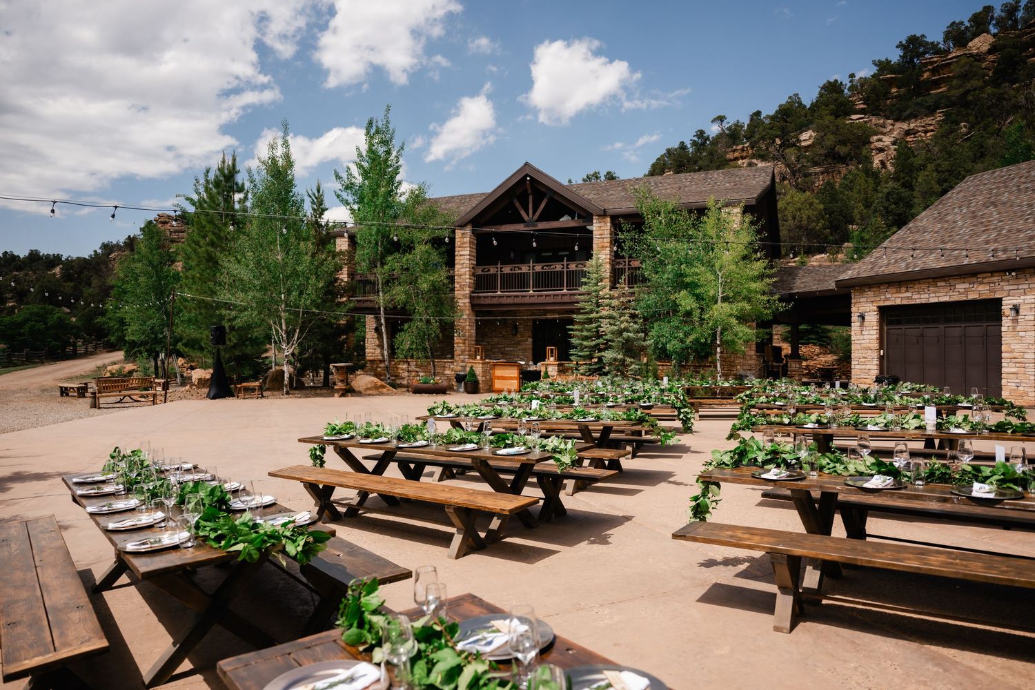 Outdoor wedding venue with wooden benches and mountain views under blue sky.