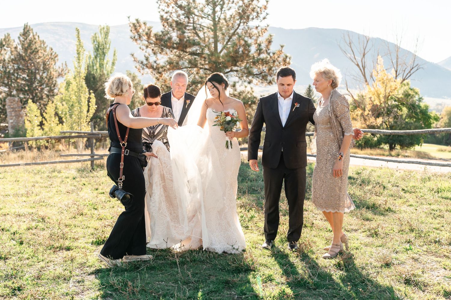 Utah Wedding Photographer adjusting brides gown during family pics during a Wolf Creek Resort wedding