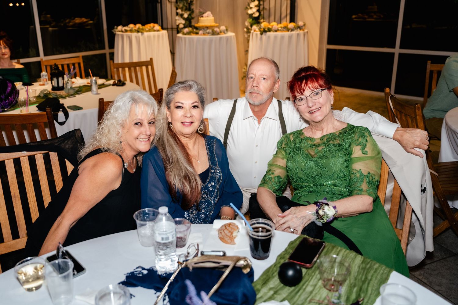 Four wedding guests sit together at a round table during an evening reception.