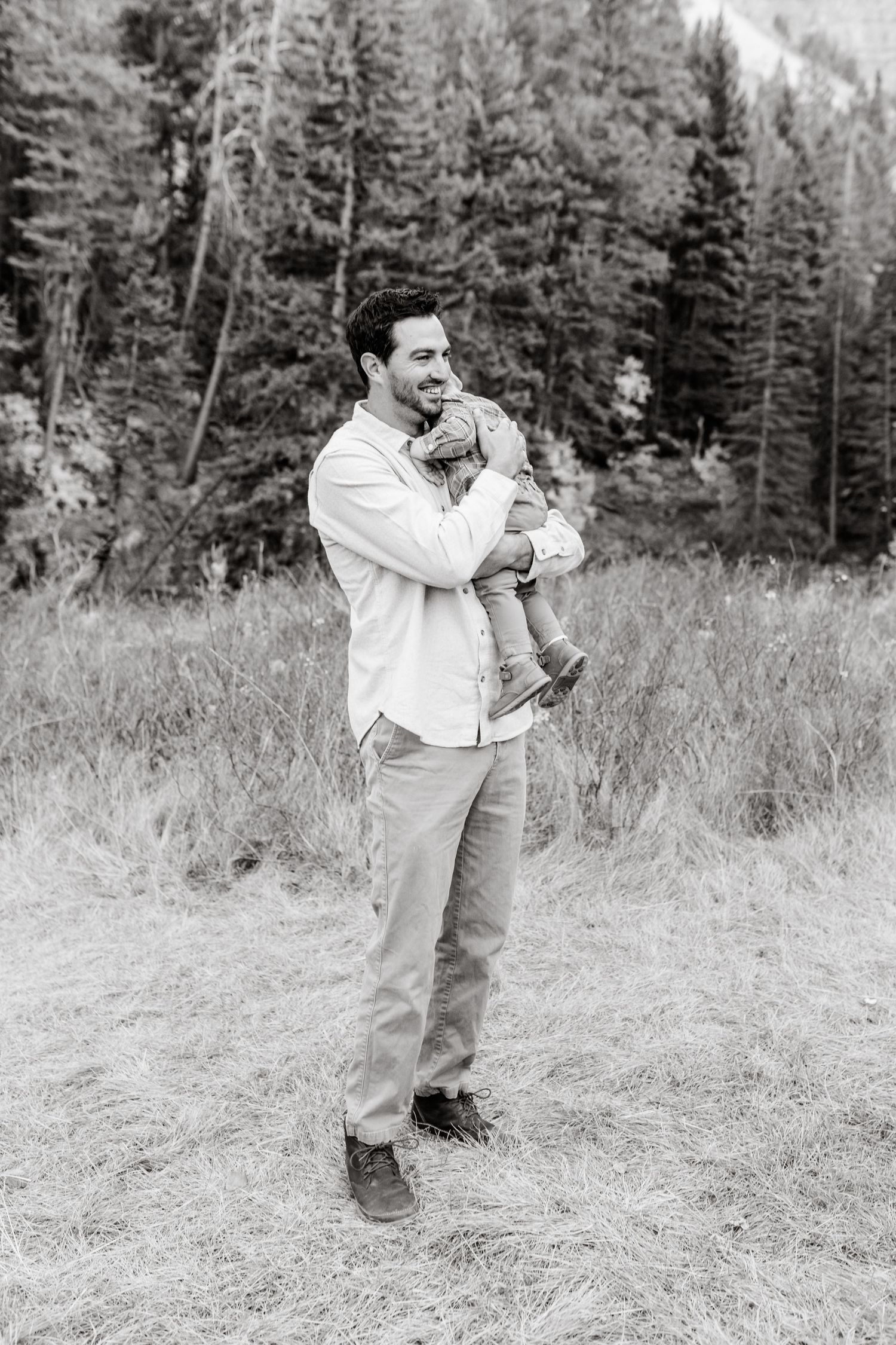 Black and white portrait of parent and child in mountain meadow.