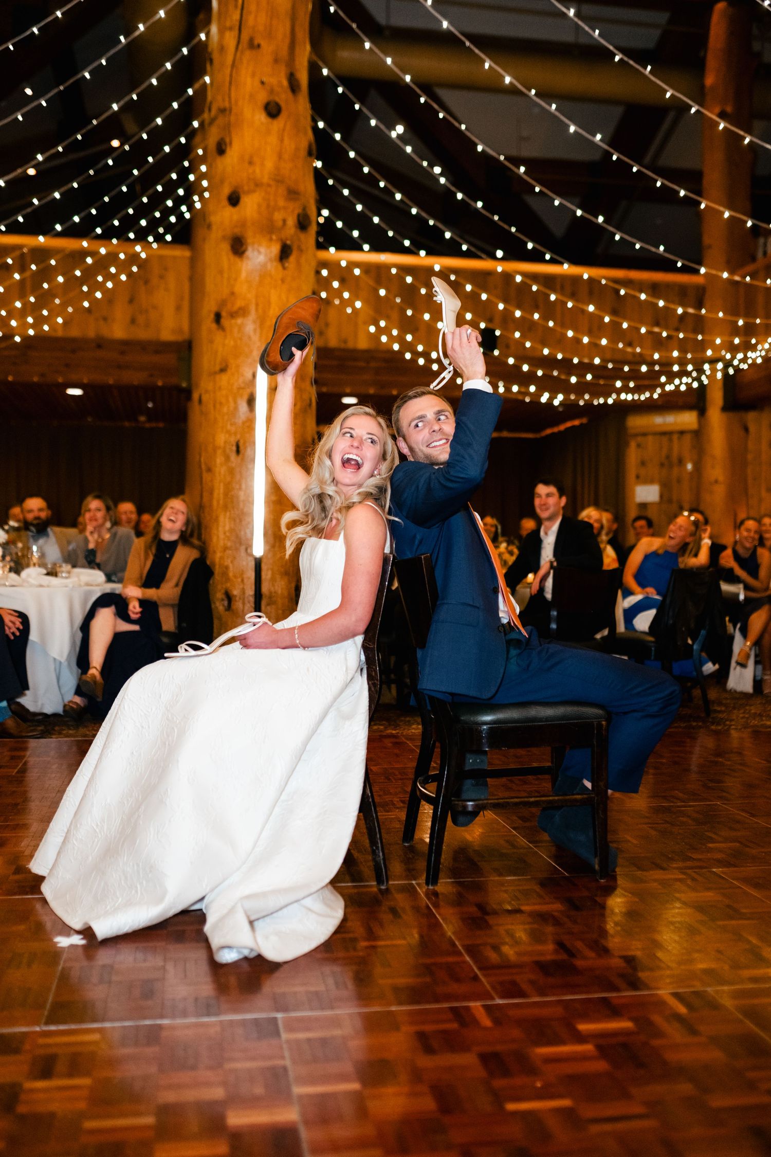 Wedding reception dance floor with twinkling string lights overhead and wooden beams creating a rustic atmosphere.