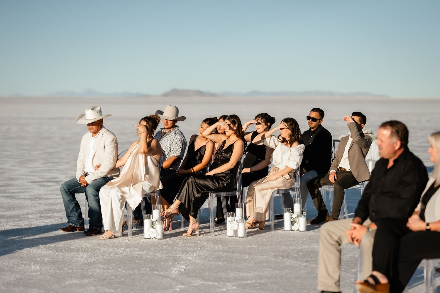Wedding guests seated in chairs on salt flats during ceremony.