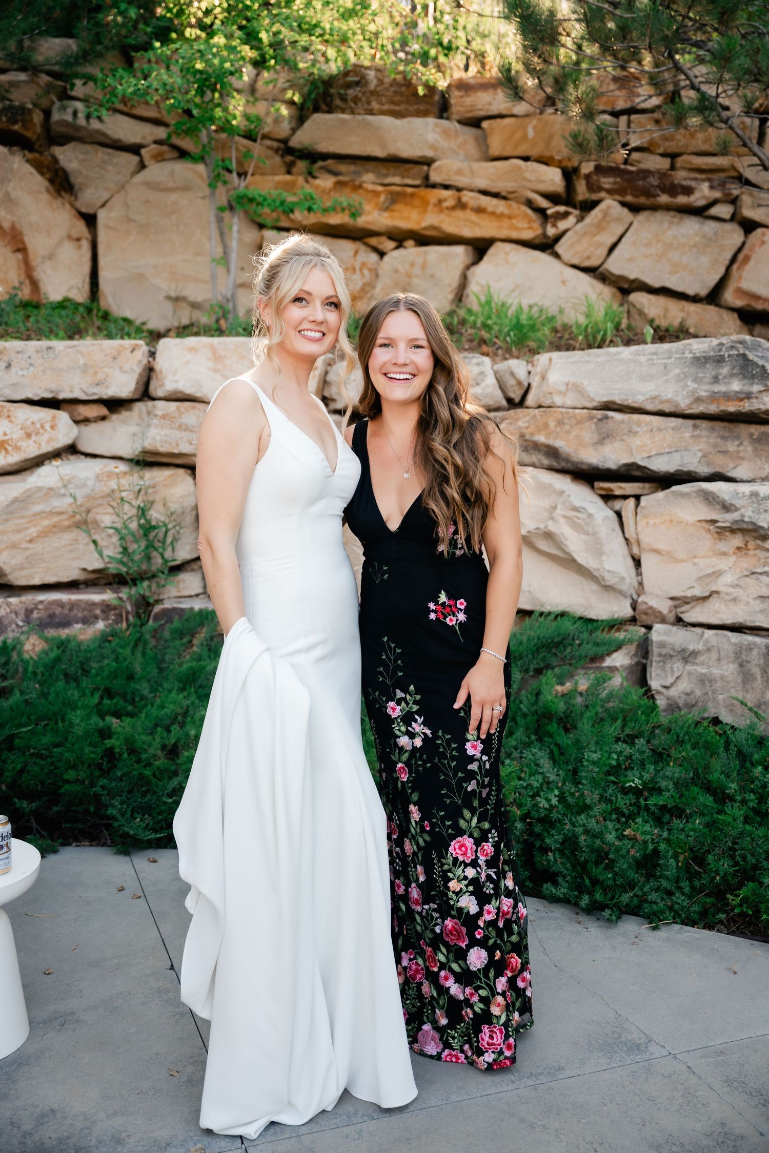 Two people posing together against a rustic stone wall backdrop at an outdoor event.