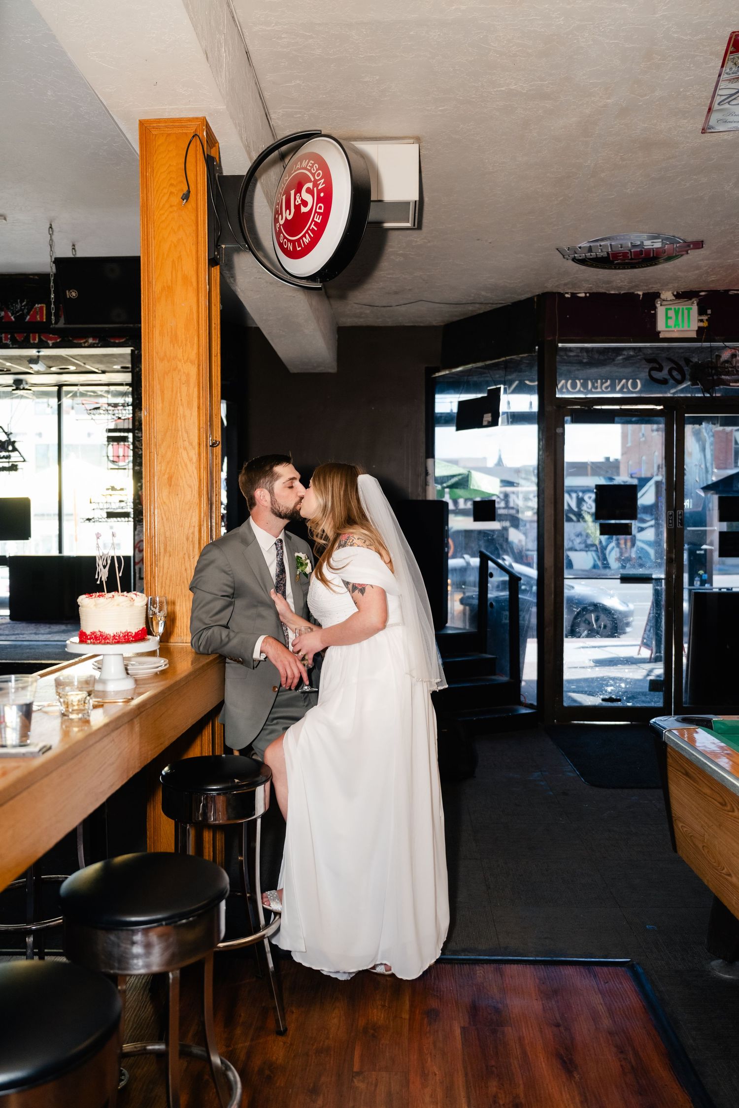 A romantic moment between newlyweds at a casual bar with vintage decor and wooden stools.