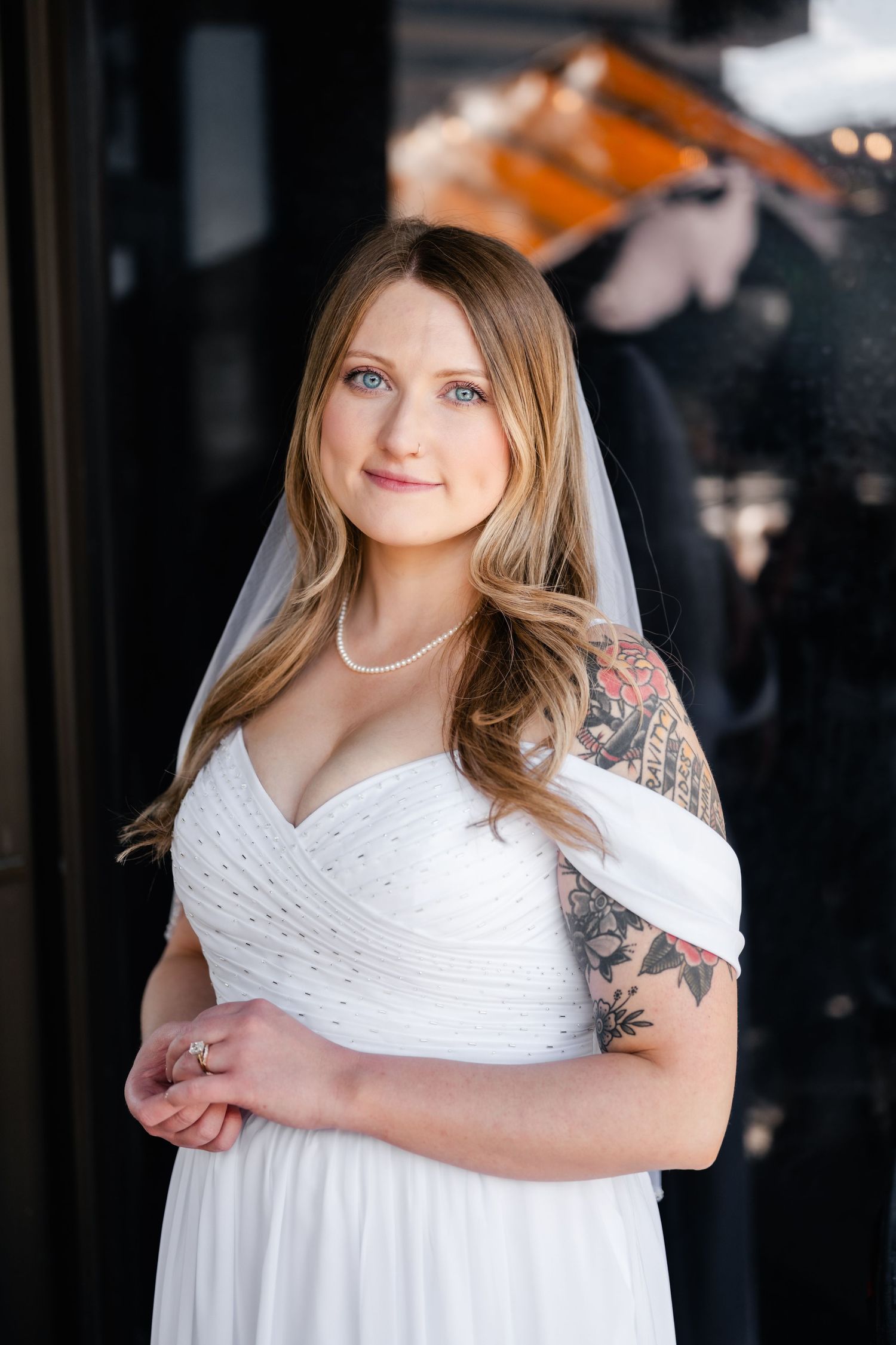 A person in a white dress poses against a dark background in a casual setting.