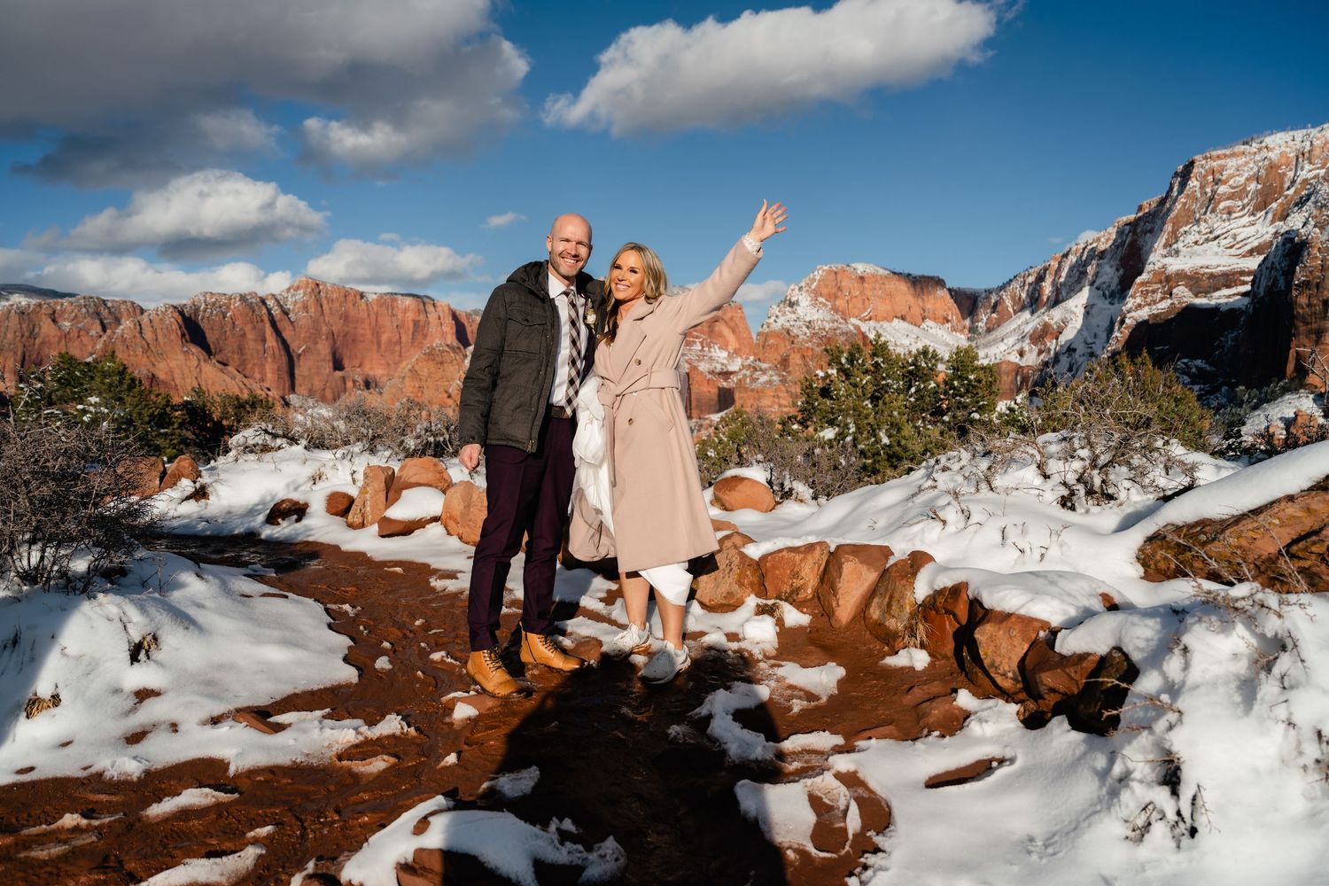 Dramatic winter landscape of snow-covered red rock formations under blue skies.