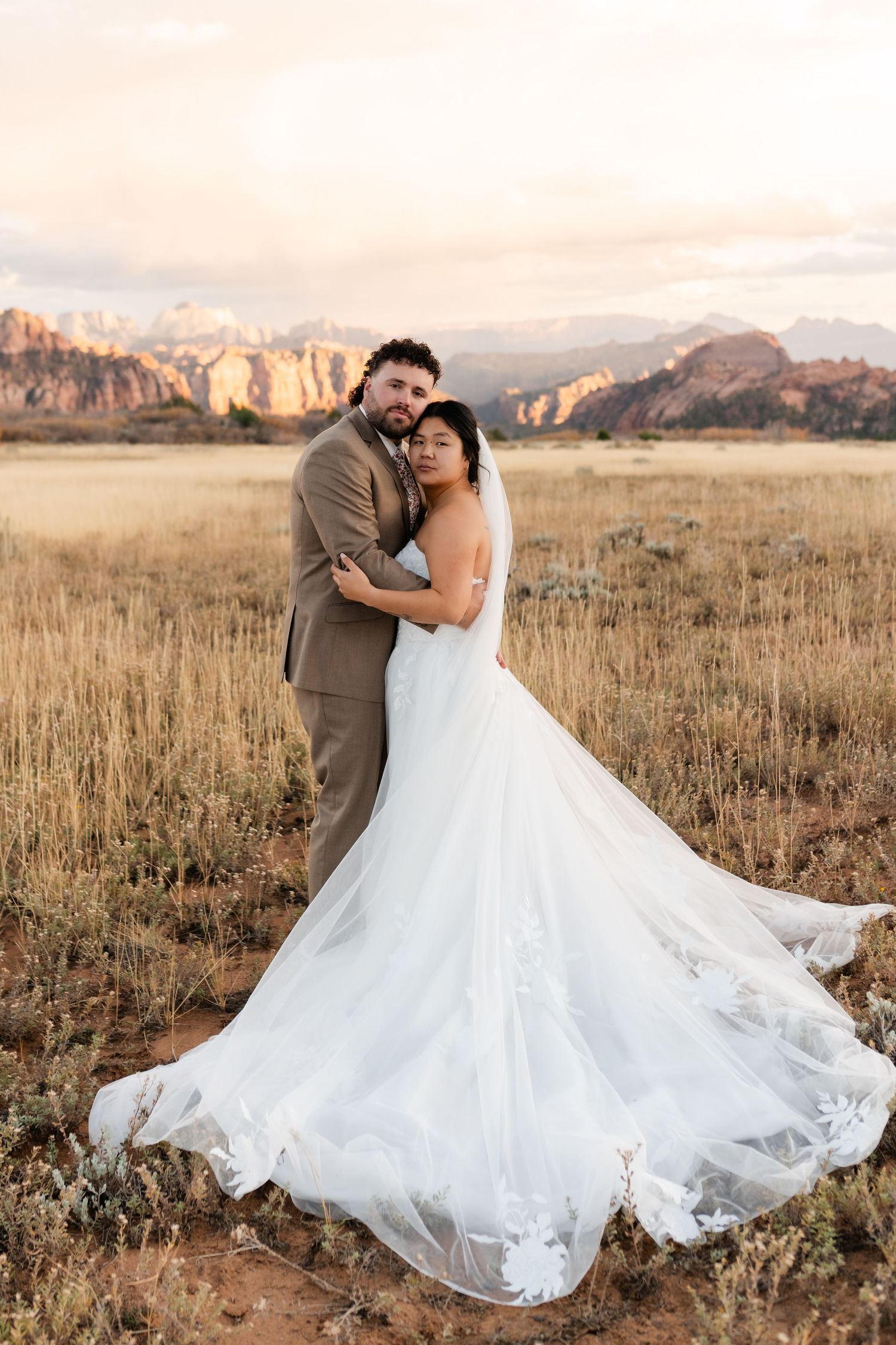 A romantic wedding dance pose in a field with dramatic mountain landscape.