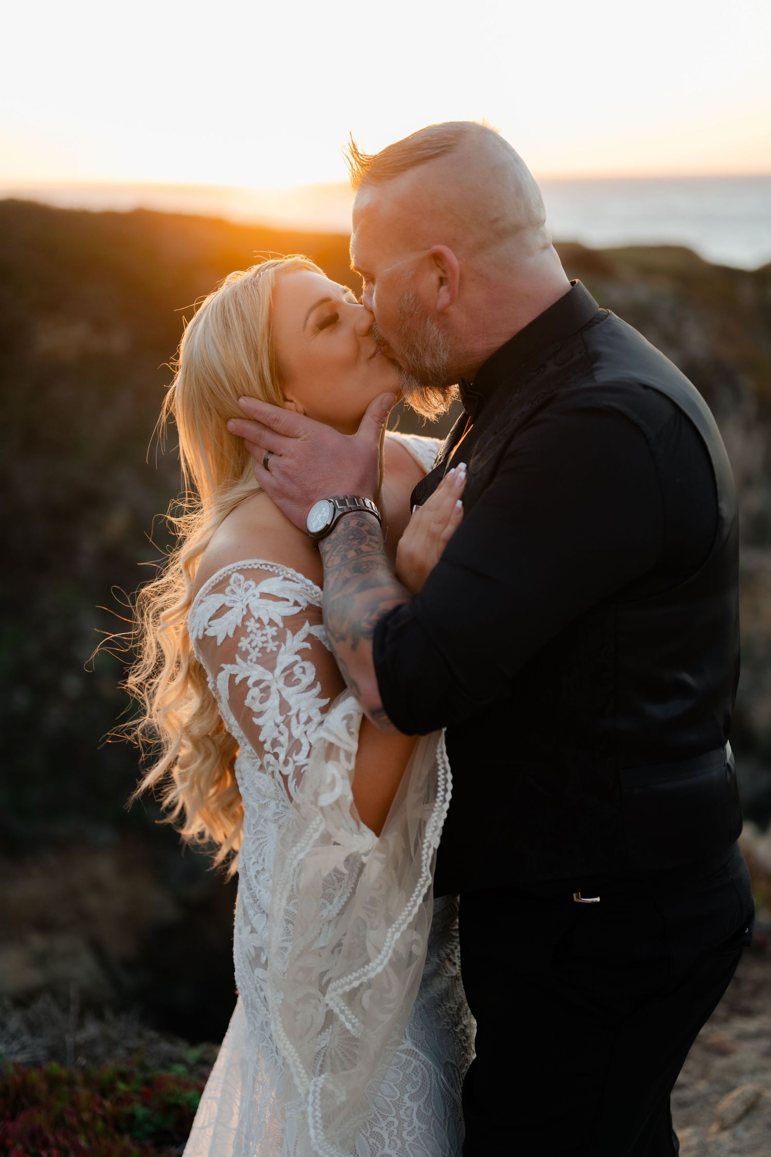 An intimate sunset moment captured between newlyweds on a coastal overlook.