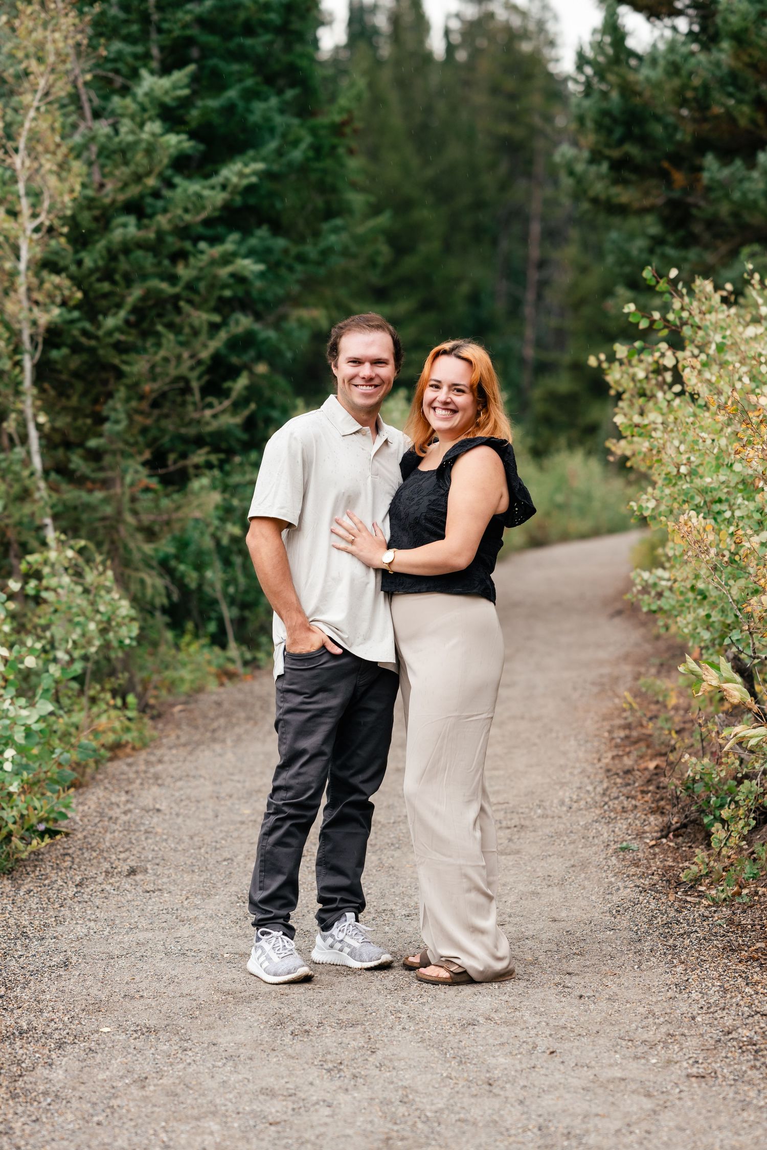 A family walks and plays together on a winding forest trail surrounded by lush greenery and trees.