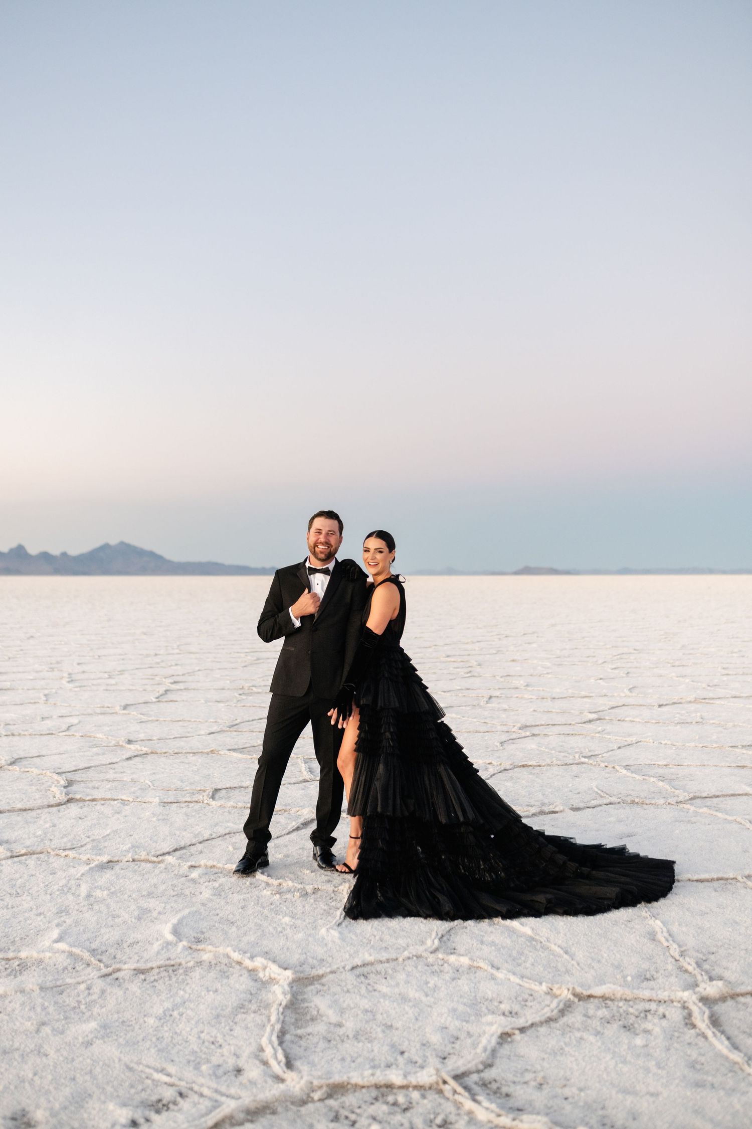Utah Salt Flats Photographer. Two people pose dramatically in formal attire on the white salt flats at dusk.