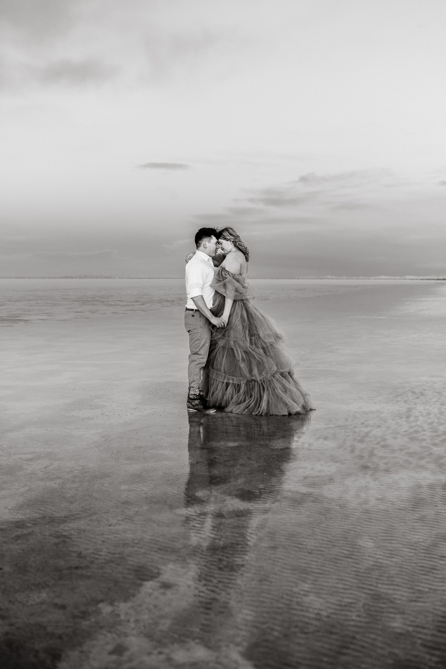 Romantic moment captured as the couple embraces amidst the serene beauty of the flooded Salt Flats during blue hour