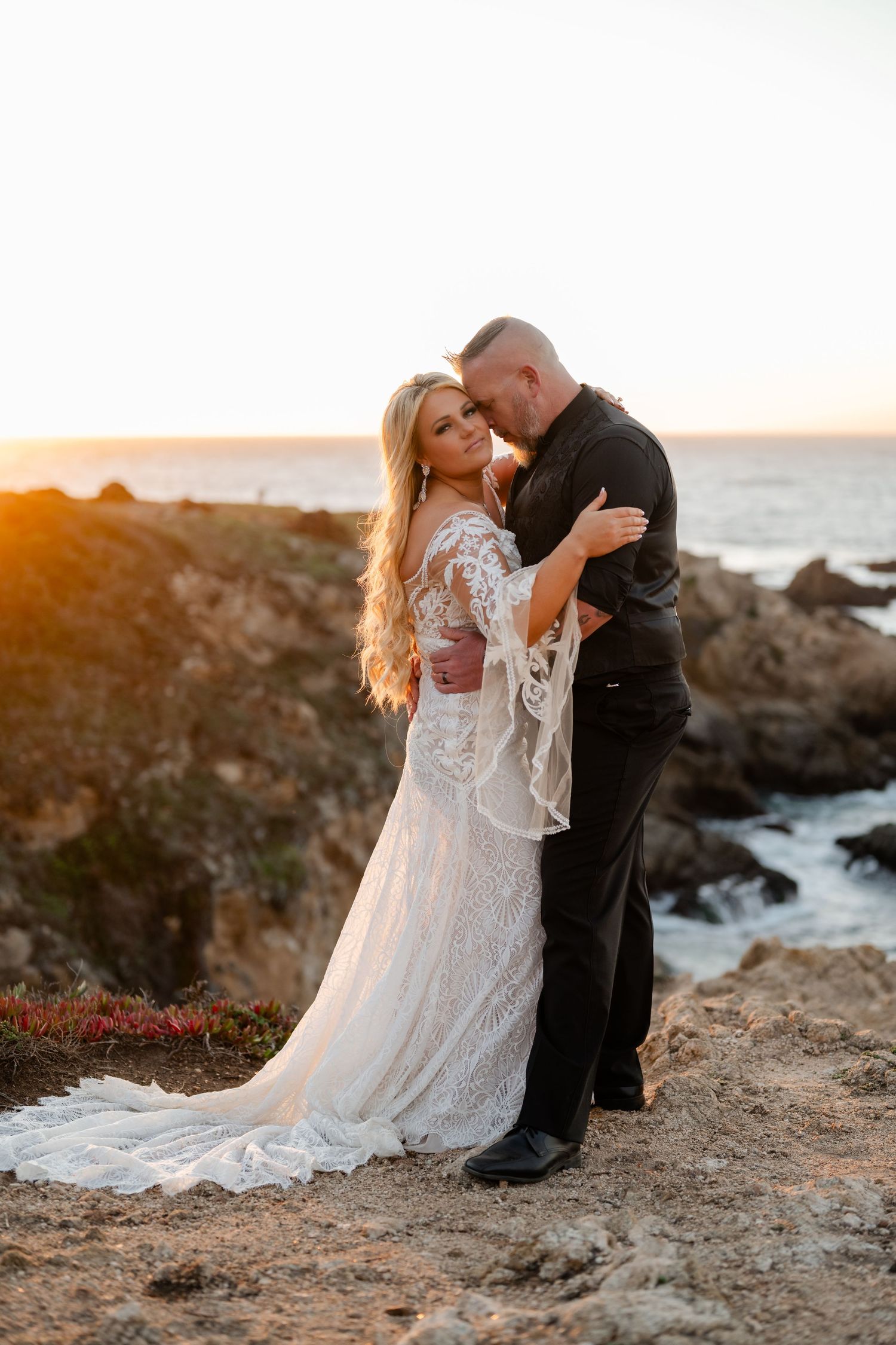 Romantic coastal wedding portraits on rocky cliffs with lace dress details and ocean backdrop.