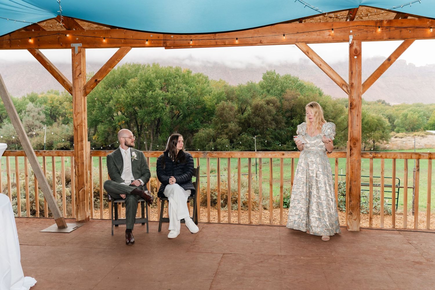 Panoramic view of rustic wooden pavilion with guests gathered for celebration.