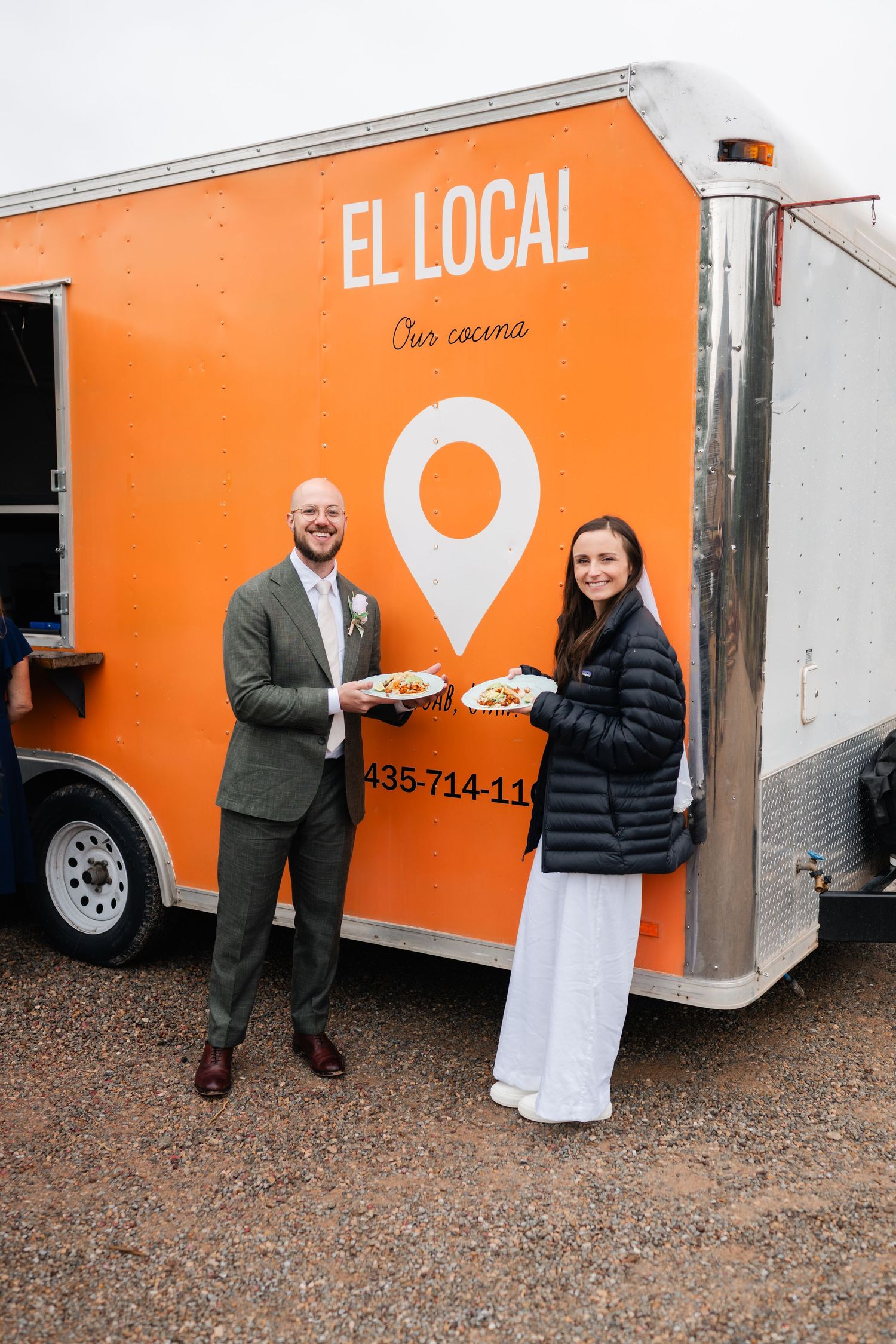 Food truck catering service with bright orange branding serves guests at outdoor event.